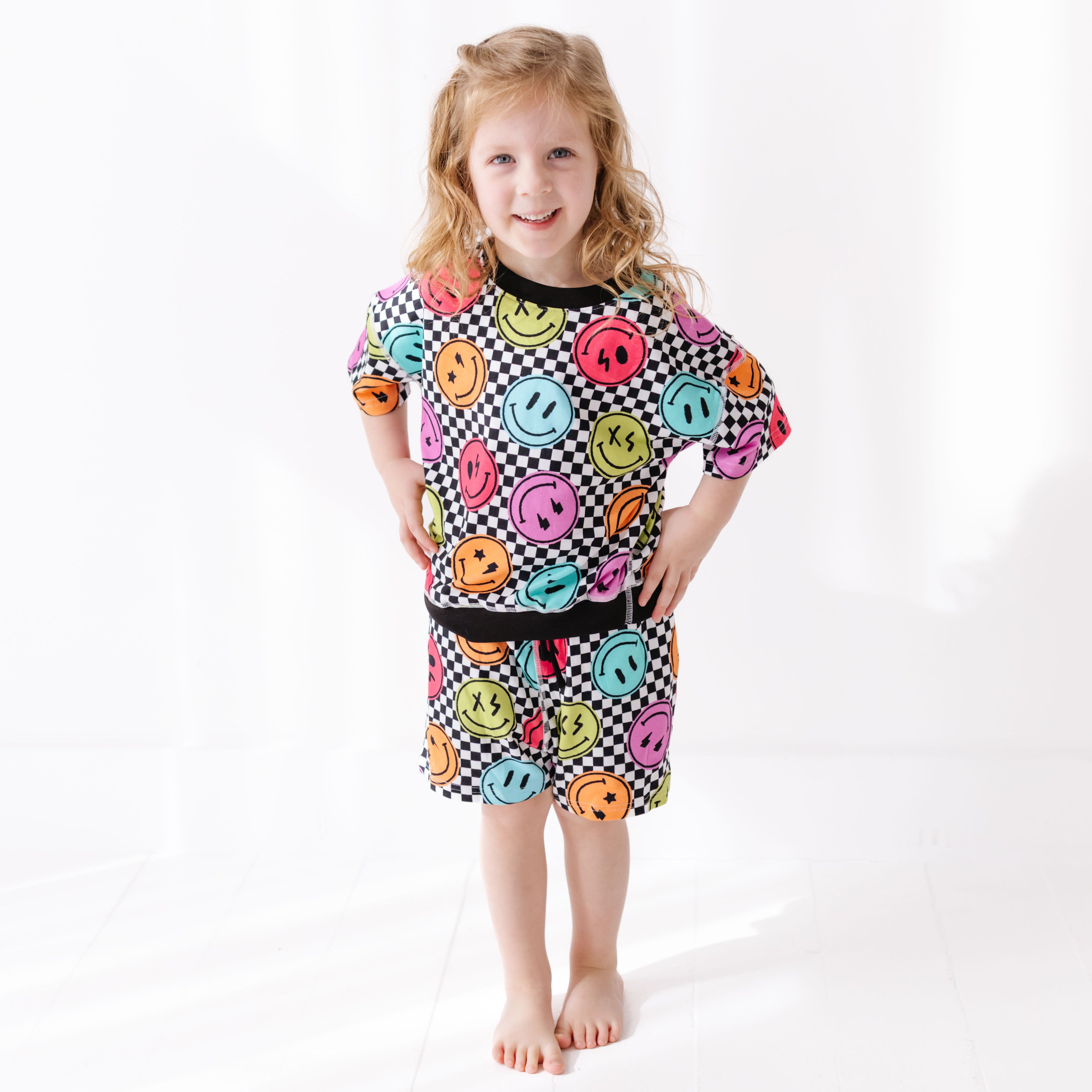 Child wearing a colorful dress with smiley face patterns on a white background