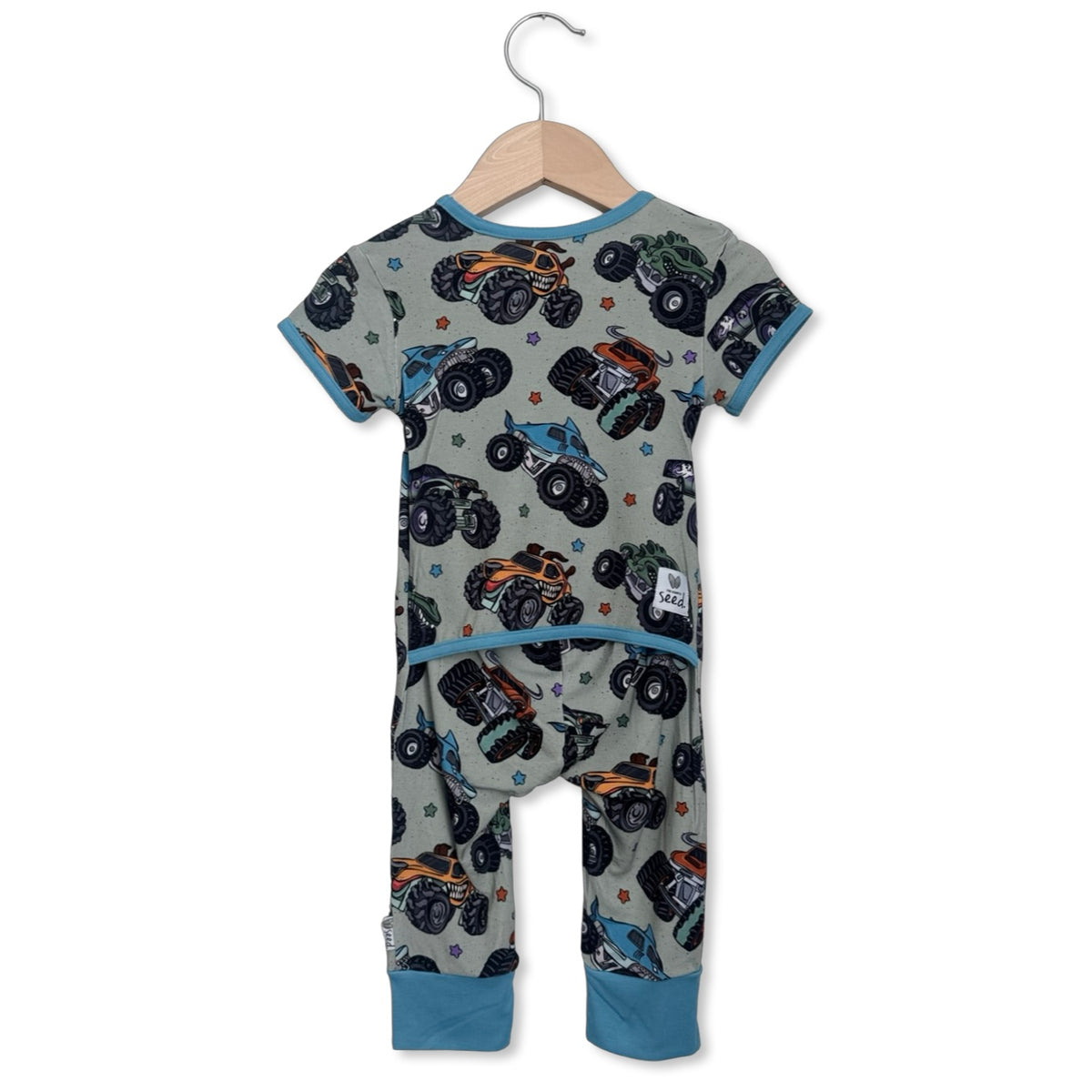 Children's onesie with monster truck pattern on a hanger against a white background