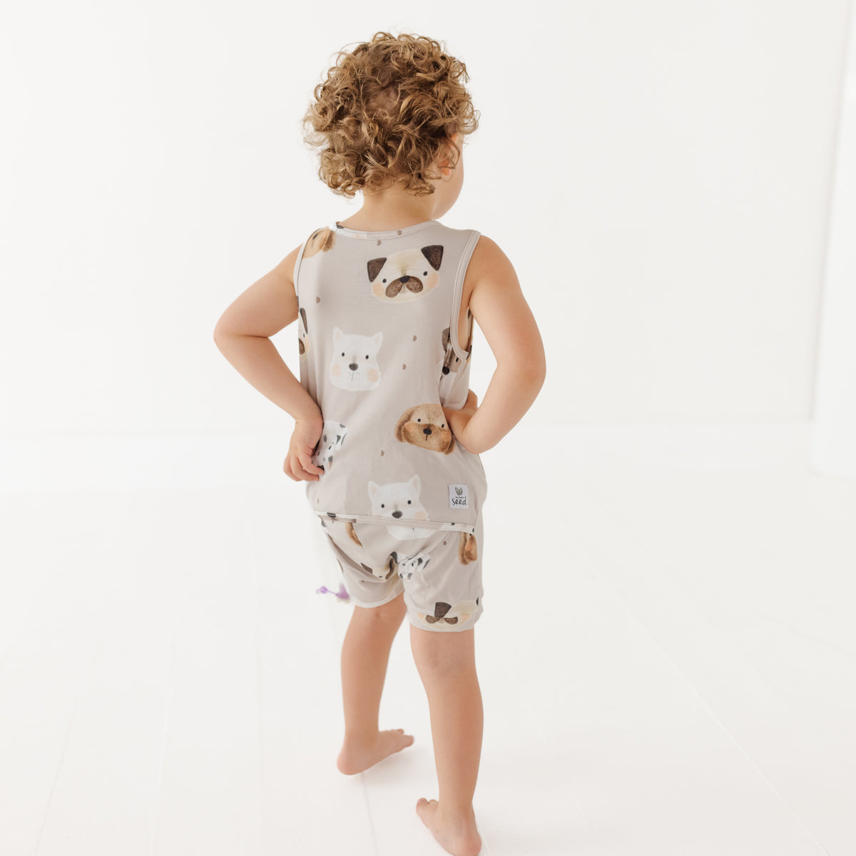 Child wearing a sleeveless romper with animal prints on a white background