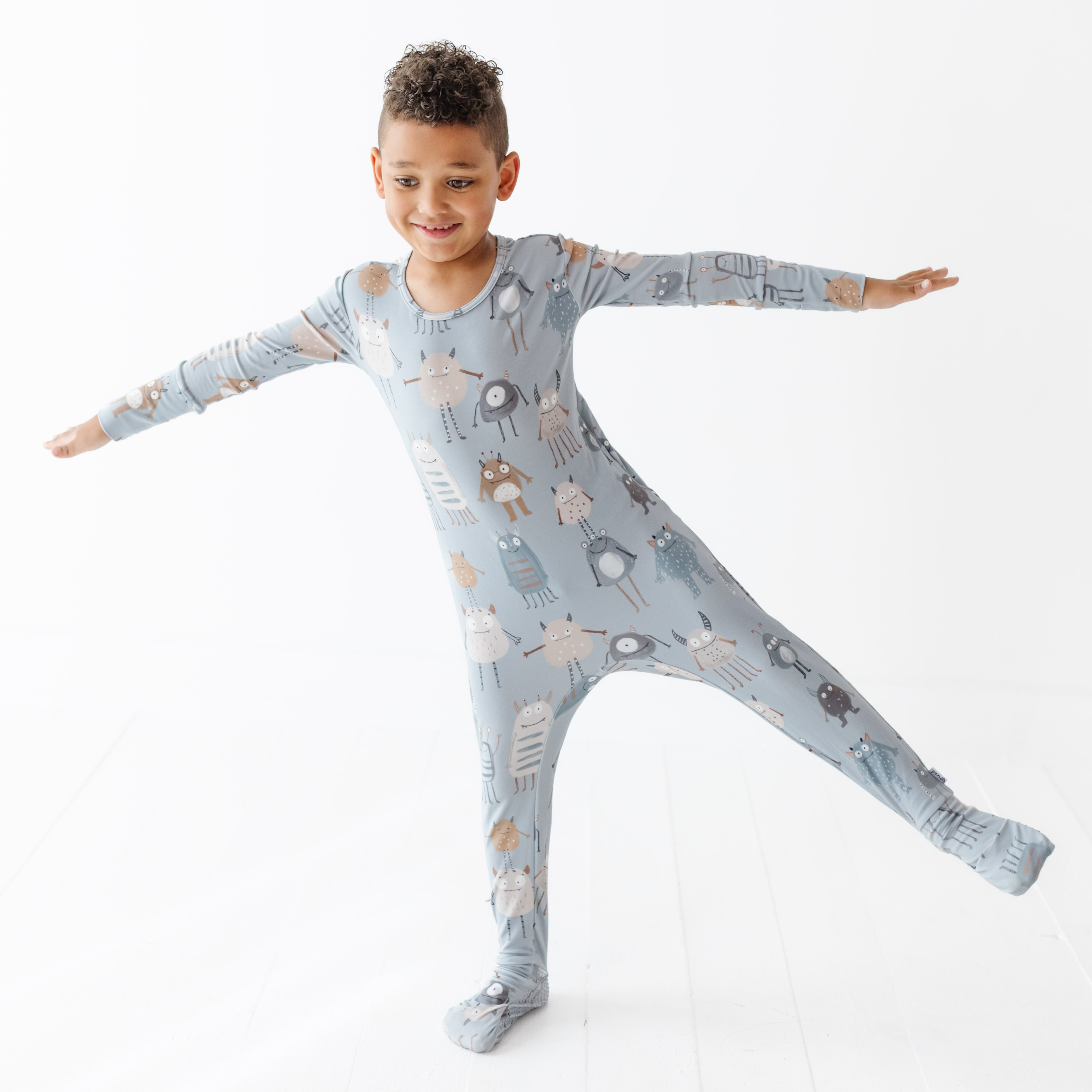 Child wearing a patterned onesie on a white background