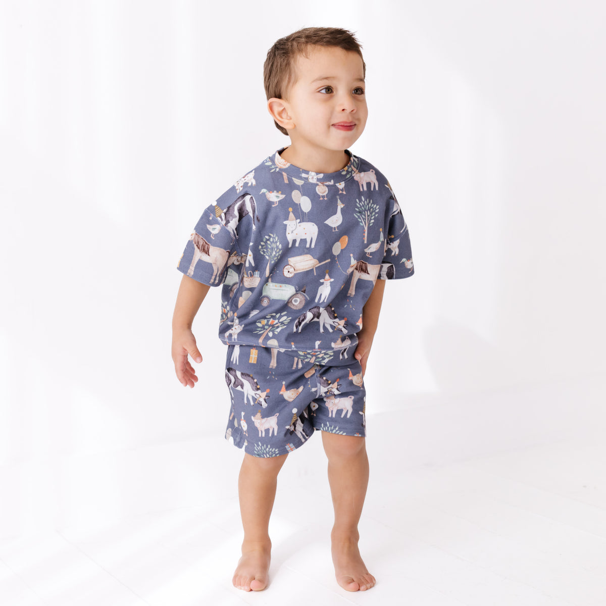 Child wearing a blue pajama set with animal prints on a white background