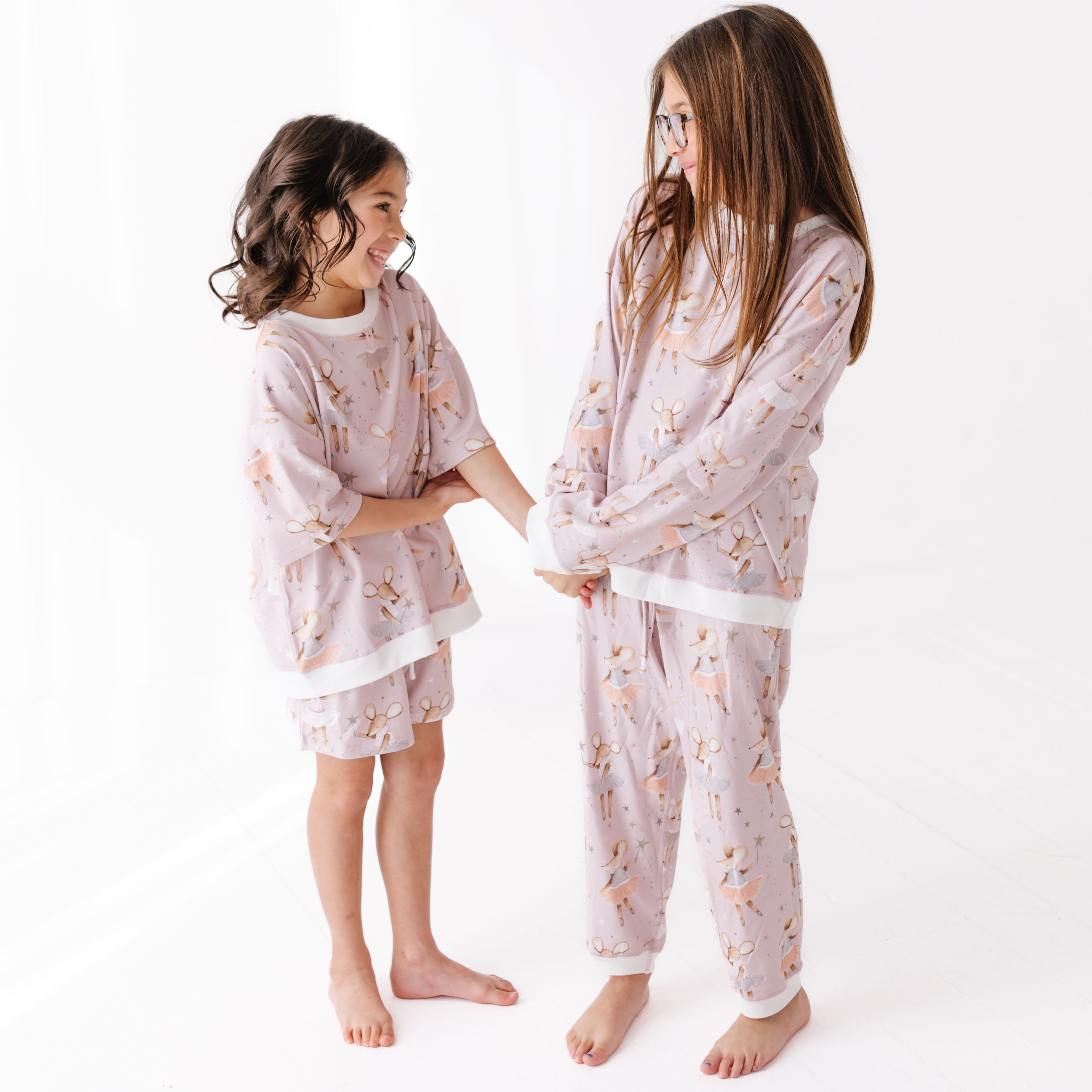 Two children wearing matching pink sweat sets with dancing mice on a white background