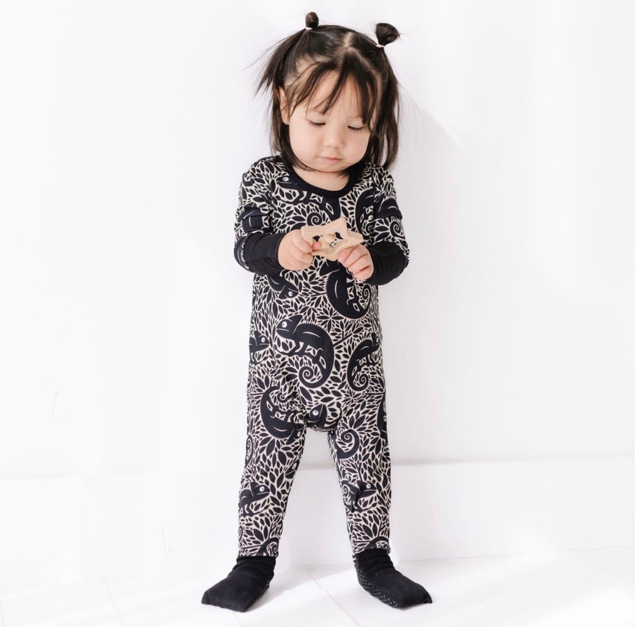 Child wearing a black and white patterned onesie on a white background