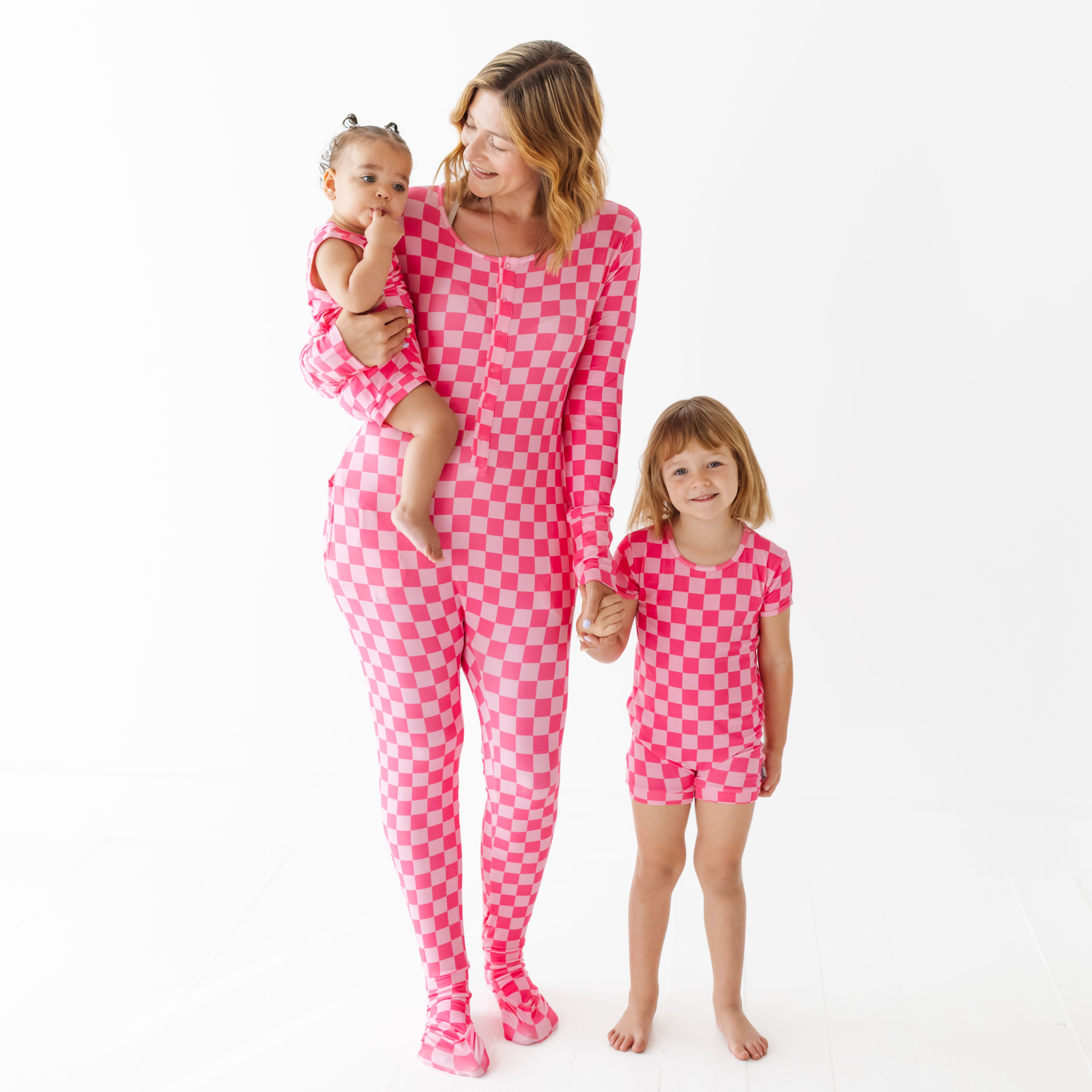 Woman and two children wearing pink checkered pajamas on a white background