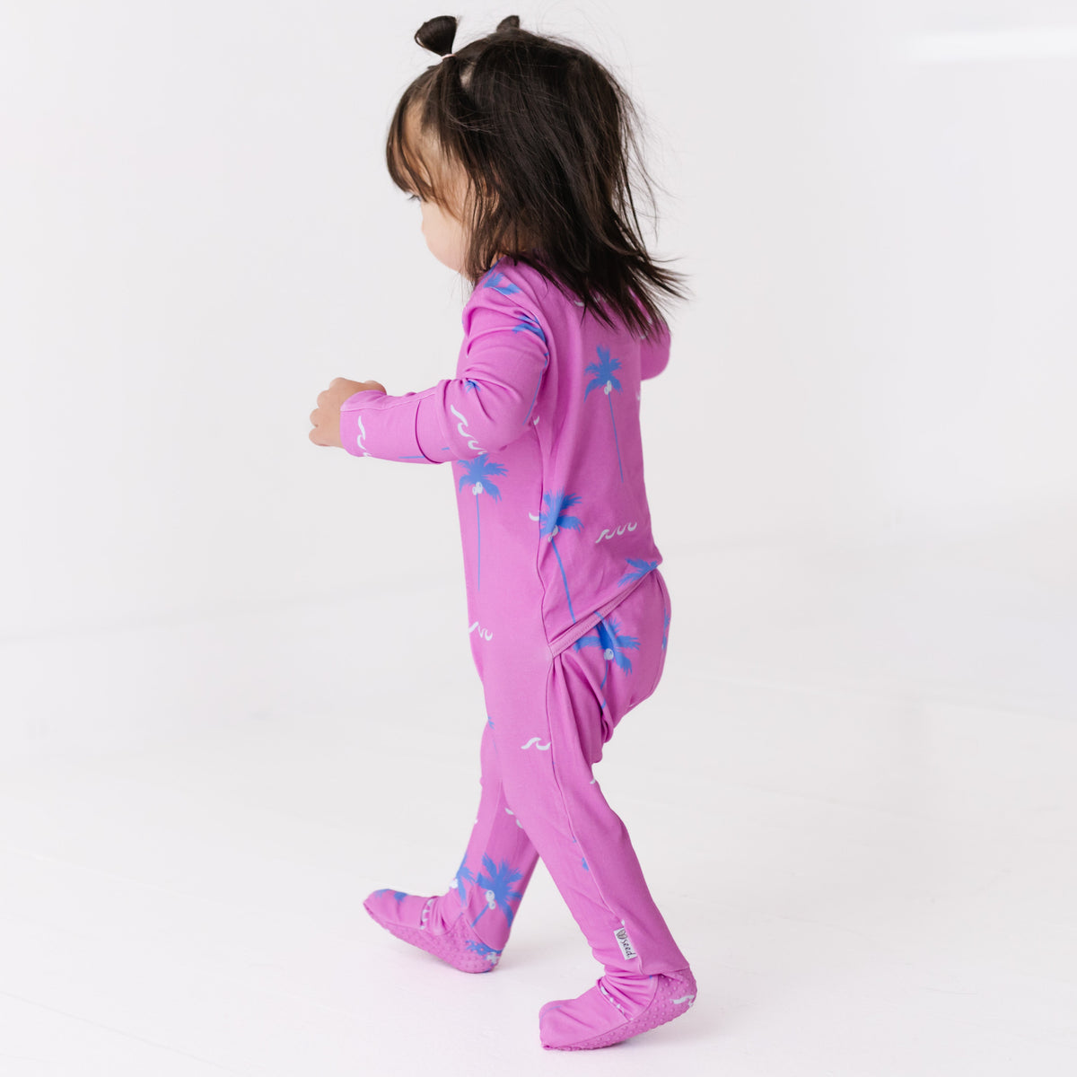Child wearing a pink onesie with blue designs on a white background