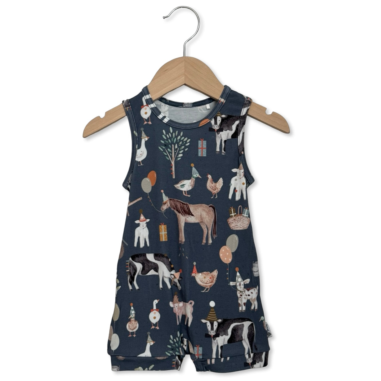 Children's navy blue romper with farm animal pattern on a wooden hanger against a white background