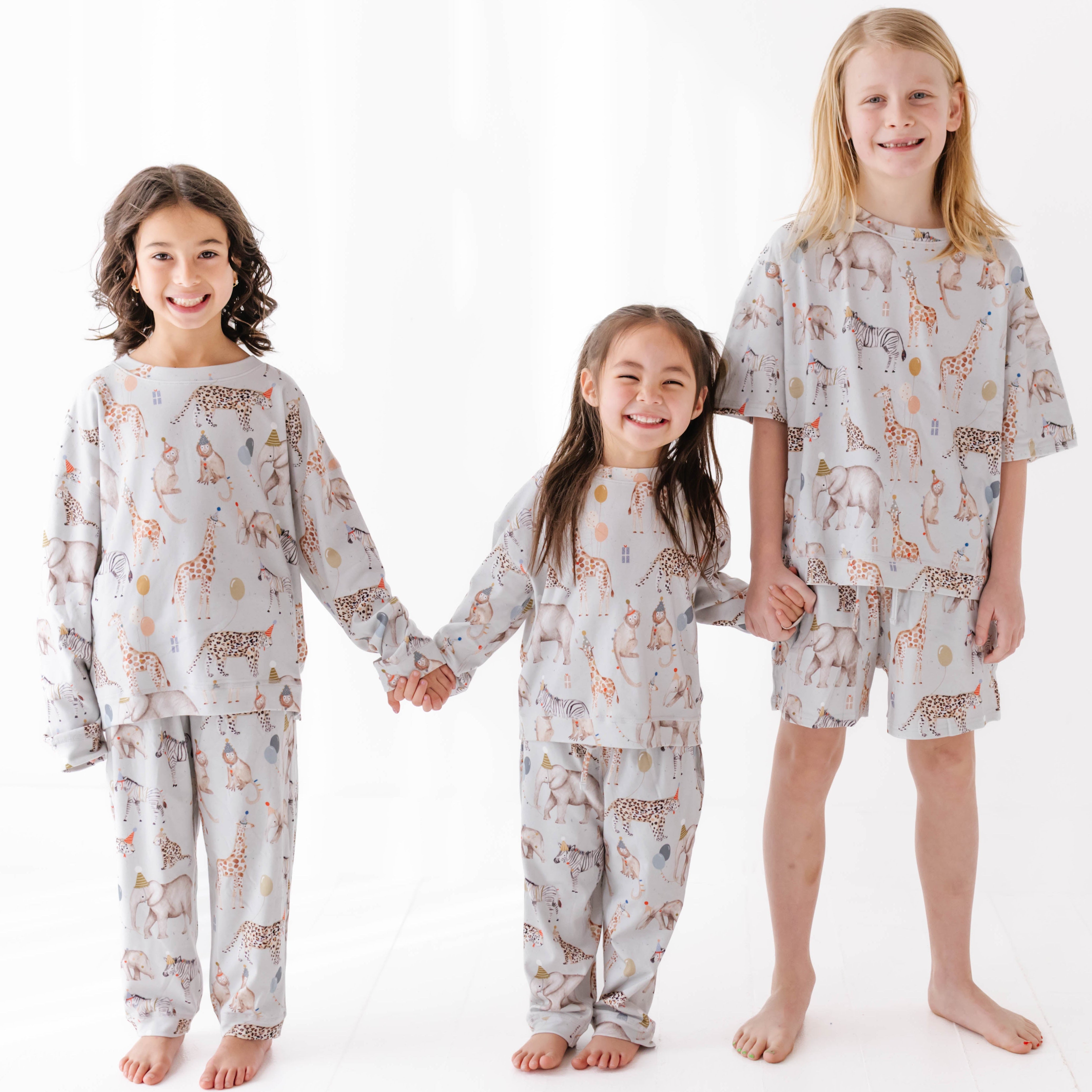 Three children wearing matching sweat set with a animal pattern on a white background