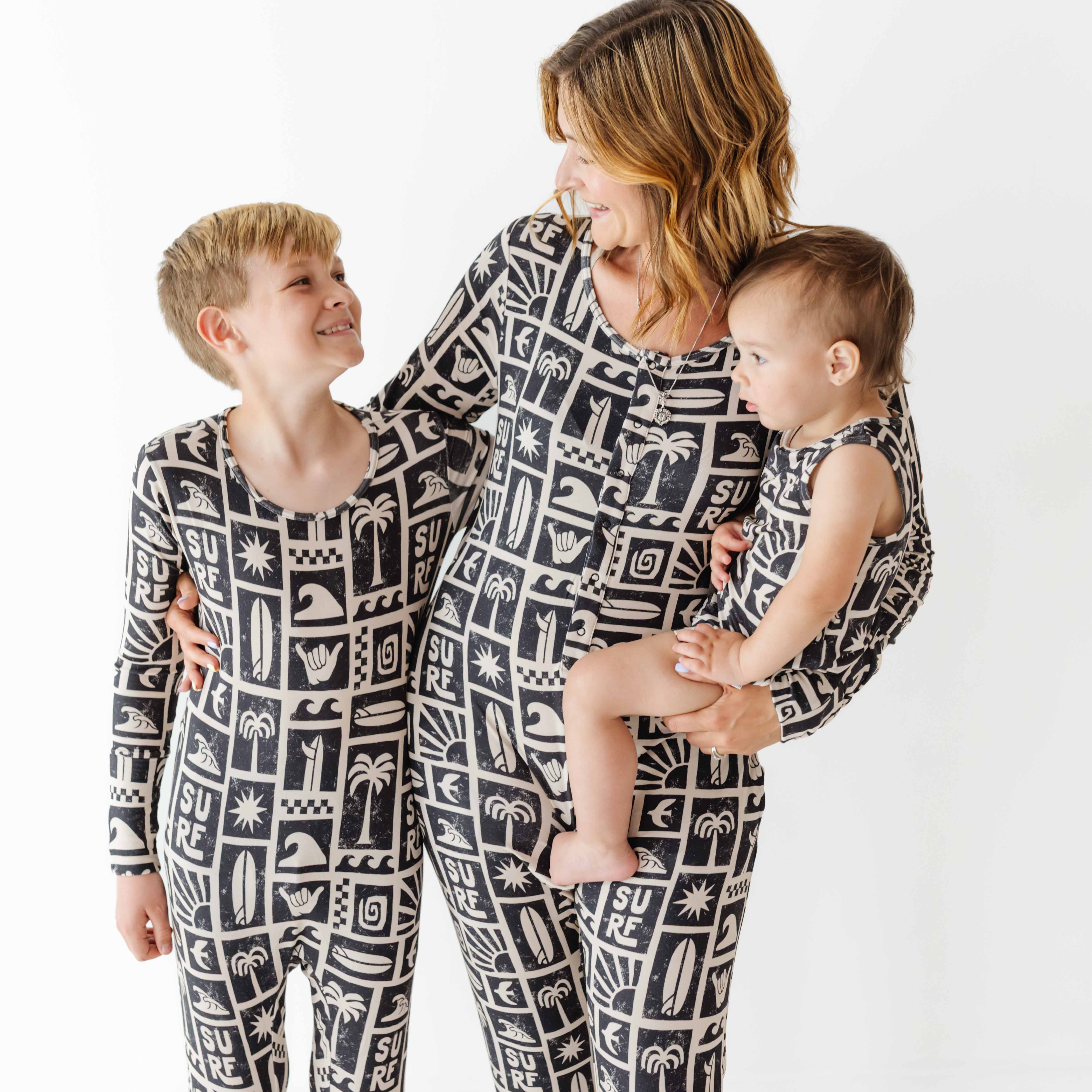 Family wearing matching black and white patterned pajamas on a white background