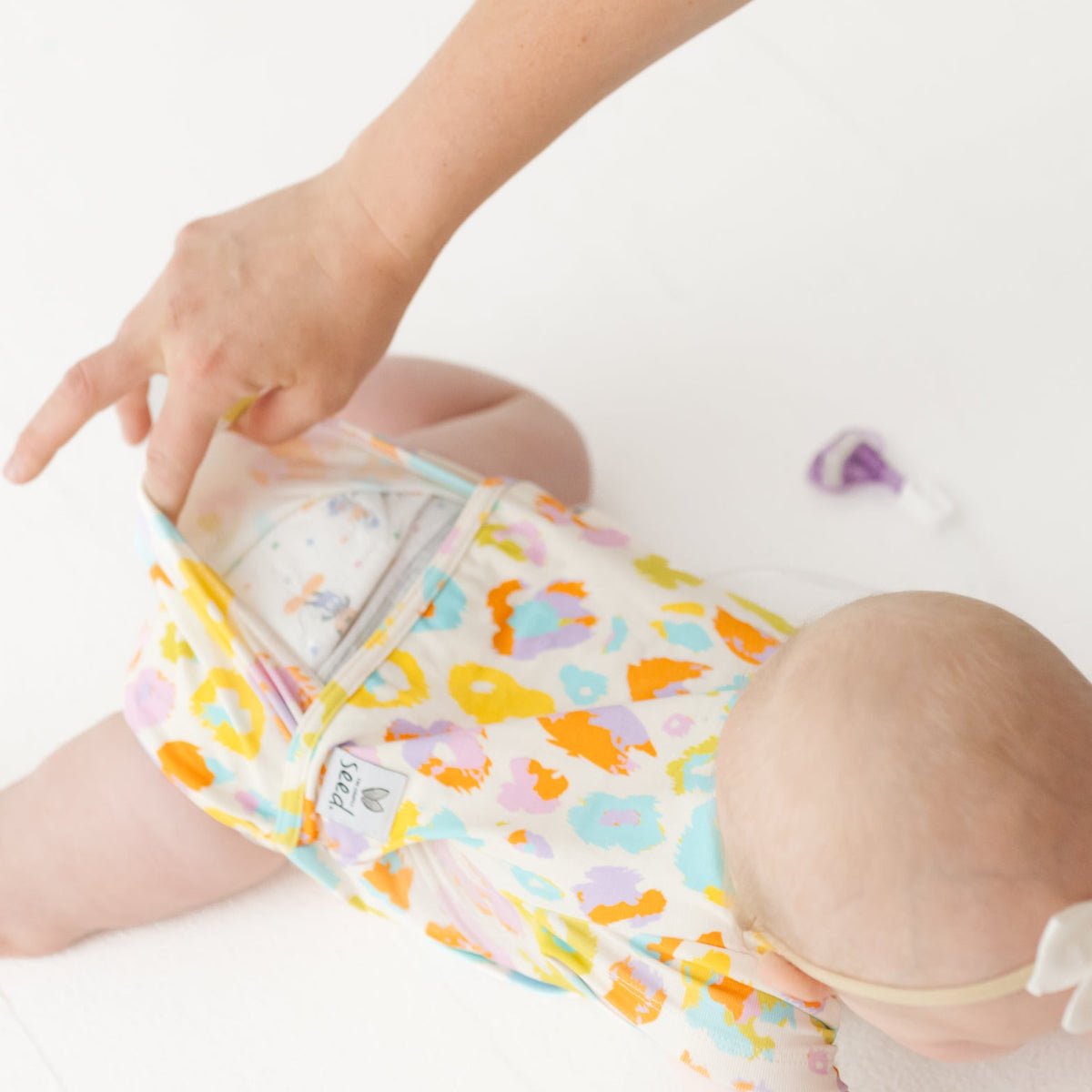 Baby wearing colorful patterned shorts with a diaper on a white background