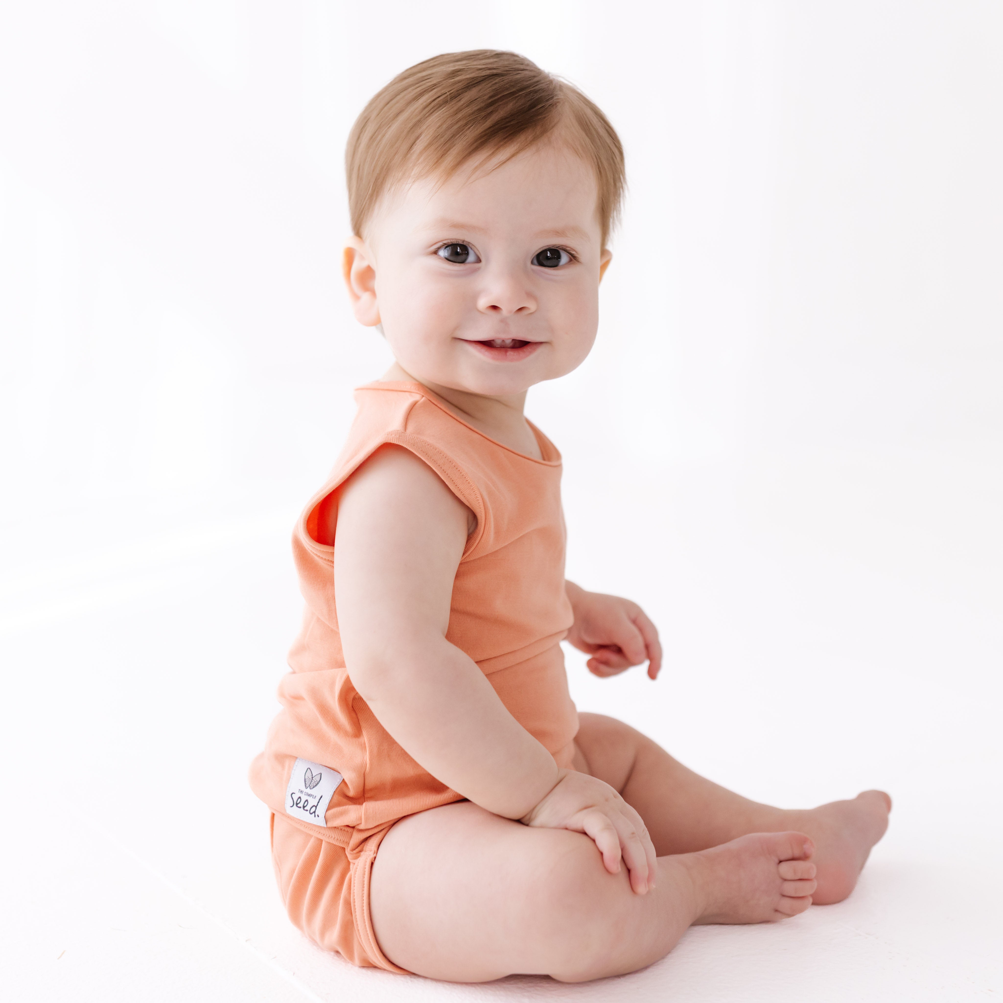 Baby wearing an orange onesie on a white background
