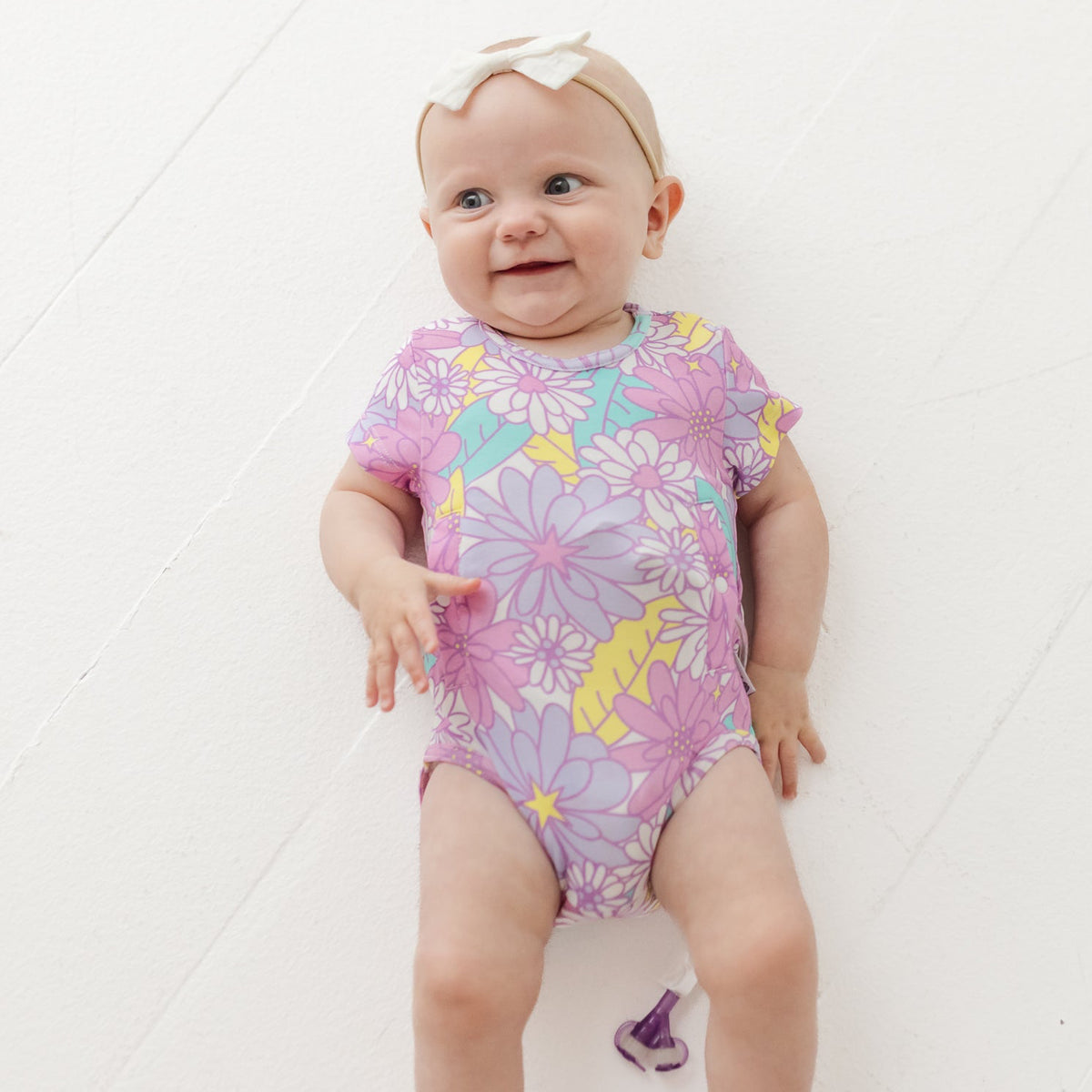 Baby wearing a colorful floral onesie on a white background