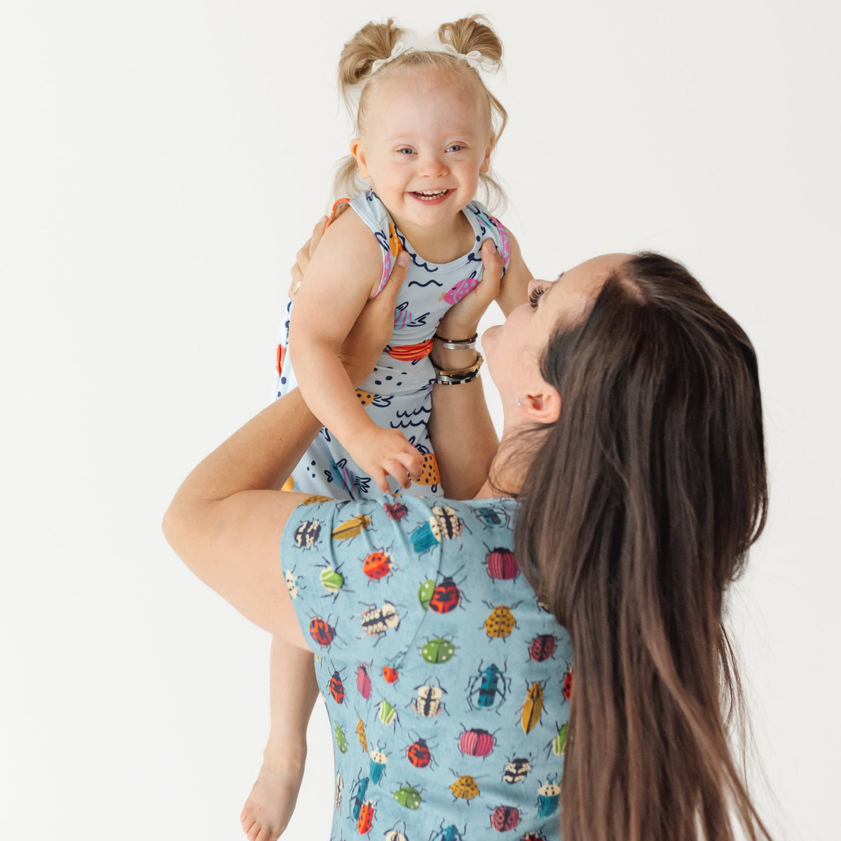 Woman and child wearing matching outfits with insect patterns on a white background