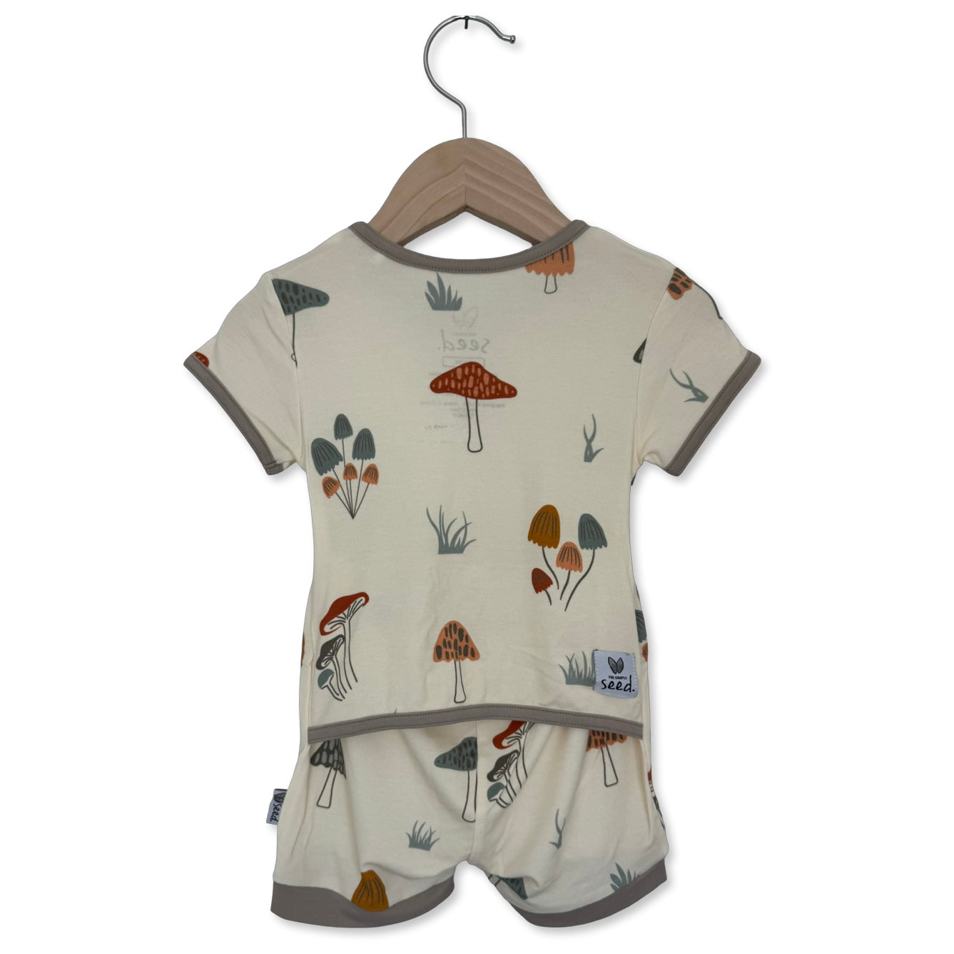 Children's outfit with mushroom pattern on a hanger against a white background