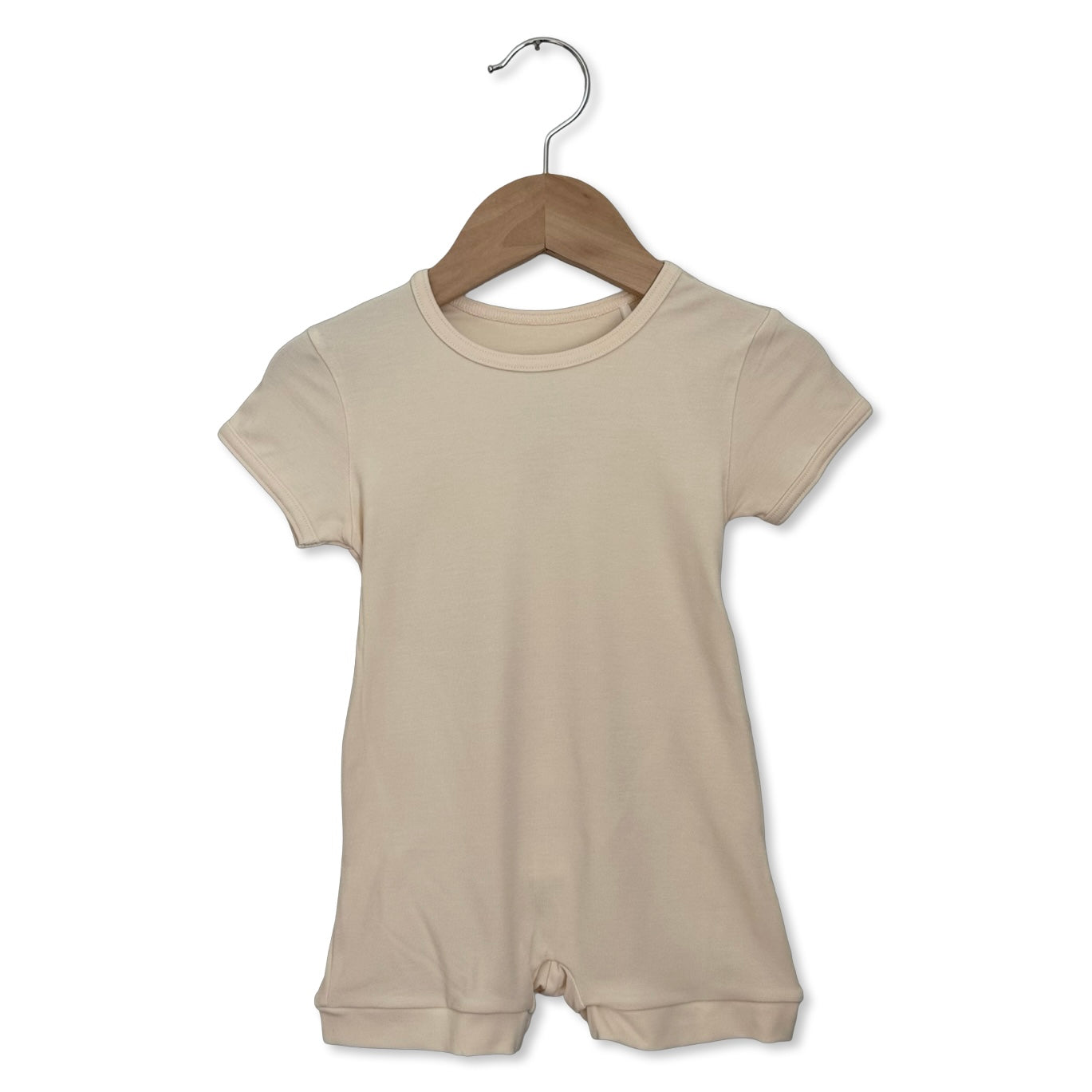 Beige baby romper on a wooden hanger against a white background