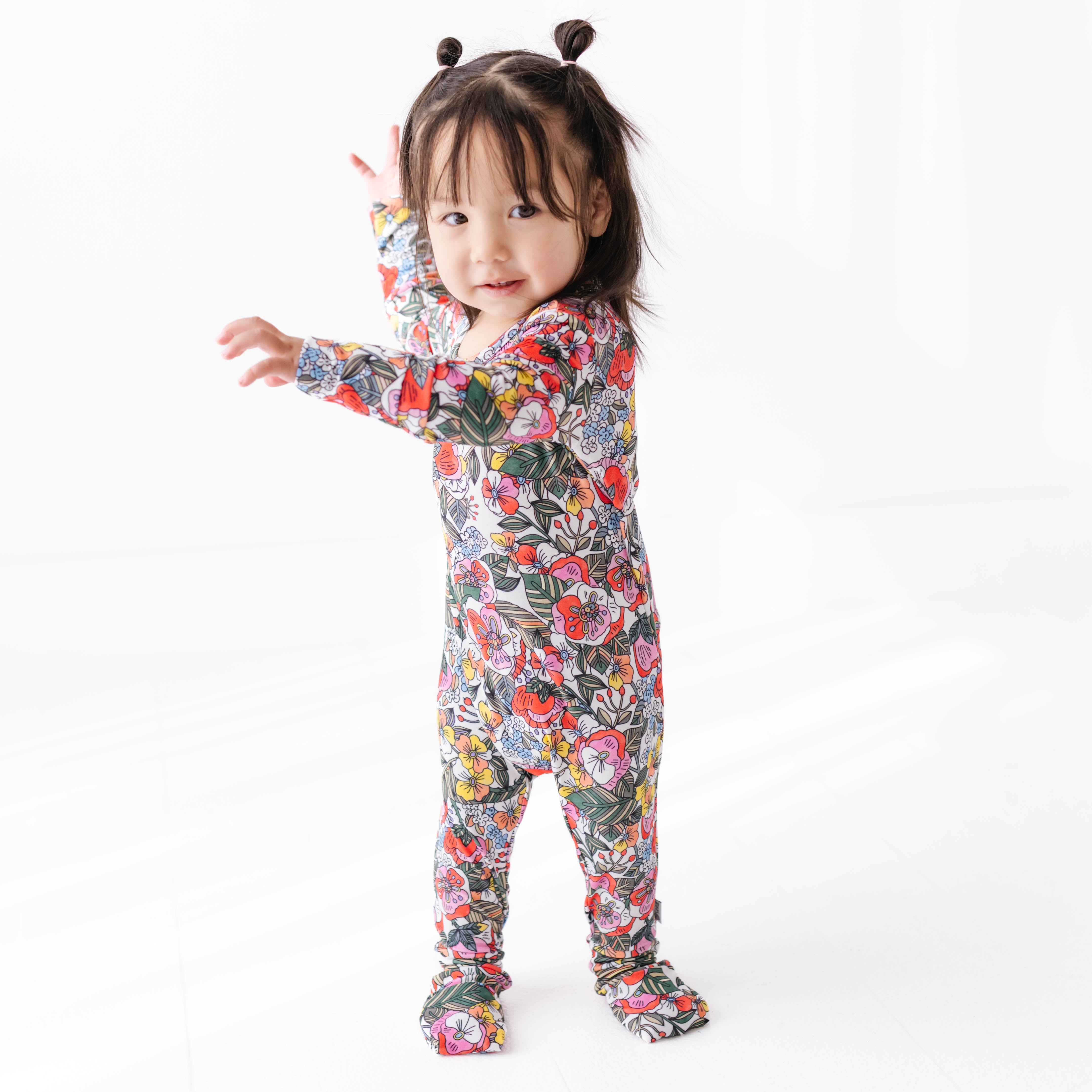 Child wearing a colorful floral onesie on a white background