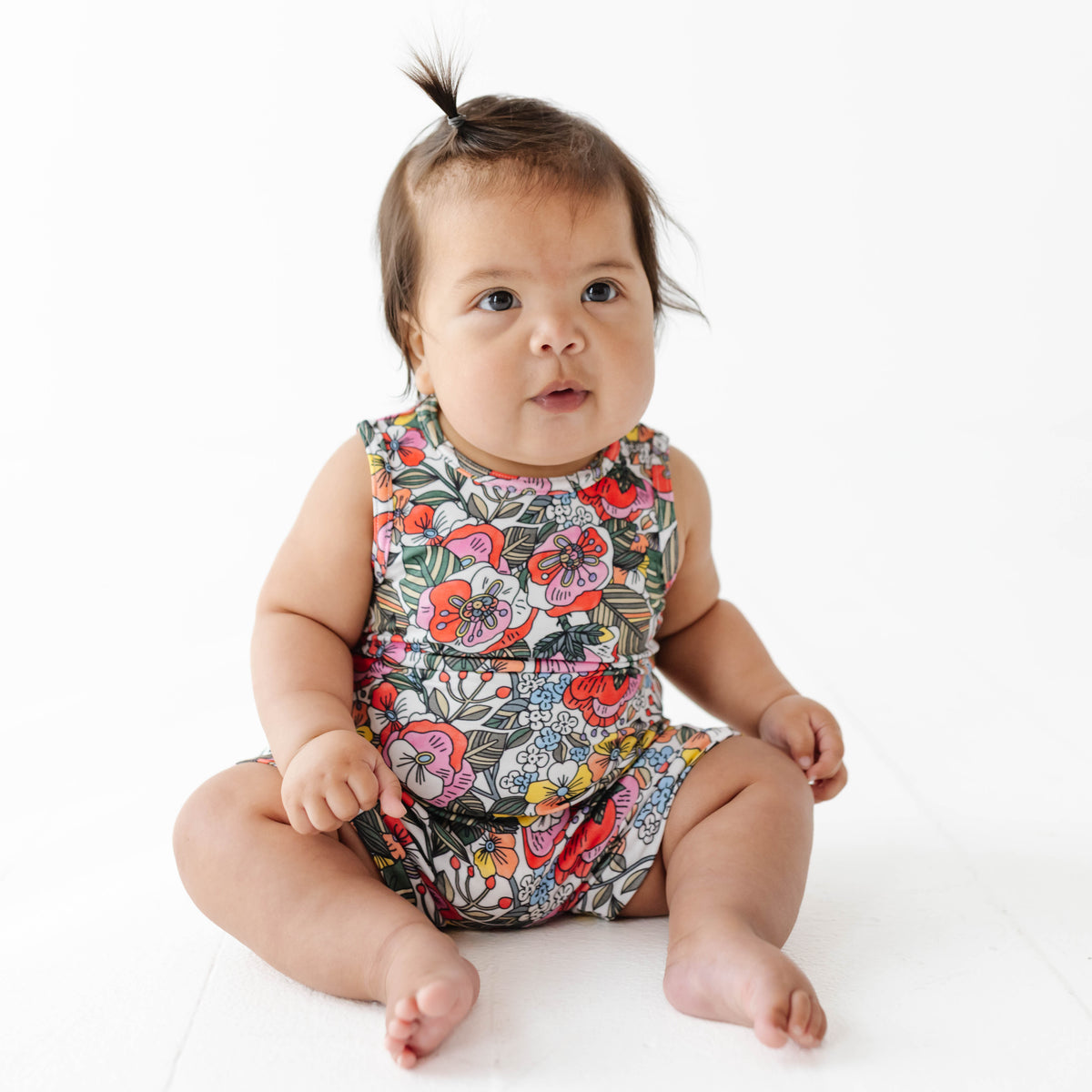 Baby wearing a colorful floral romper on a white background