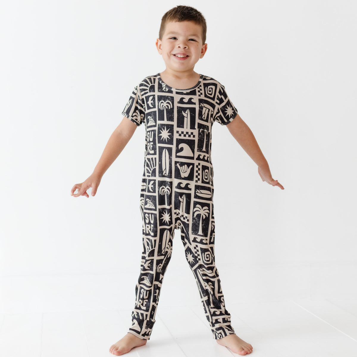 Child wearing a black and white patterned onesie on a white background