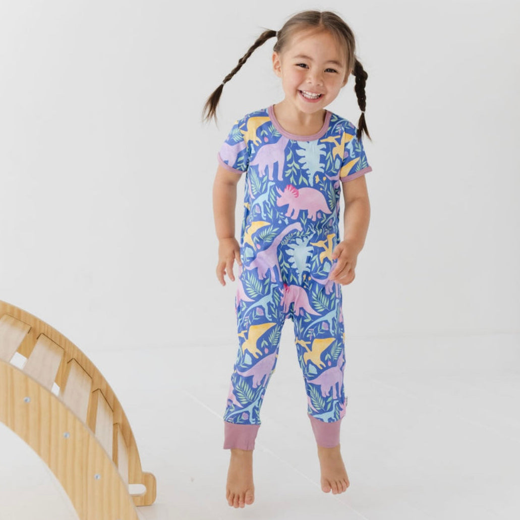 Child wearing a colorful dinosaur-themed onesie on a white background