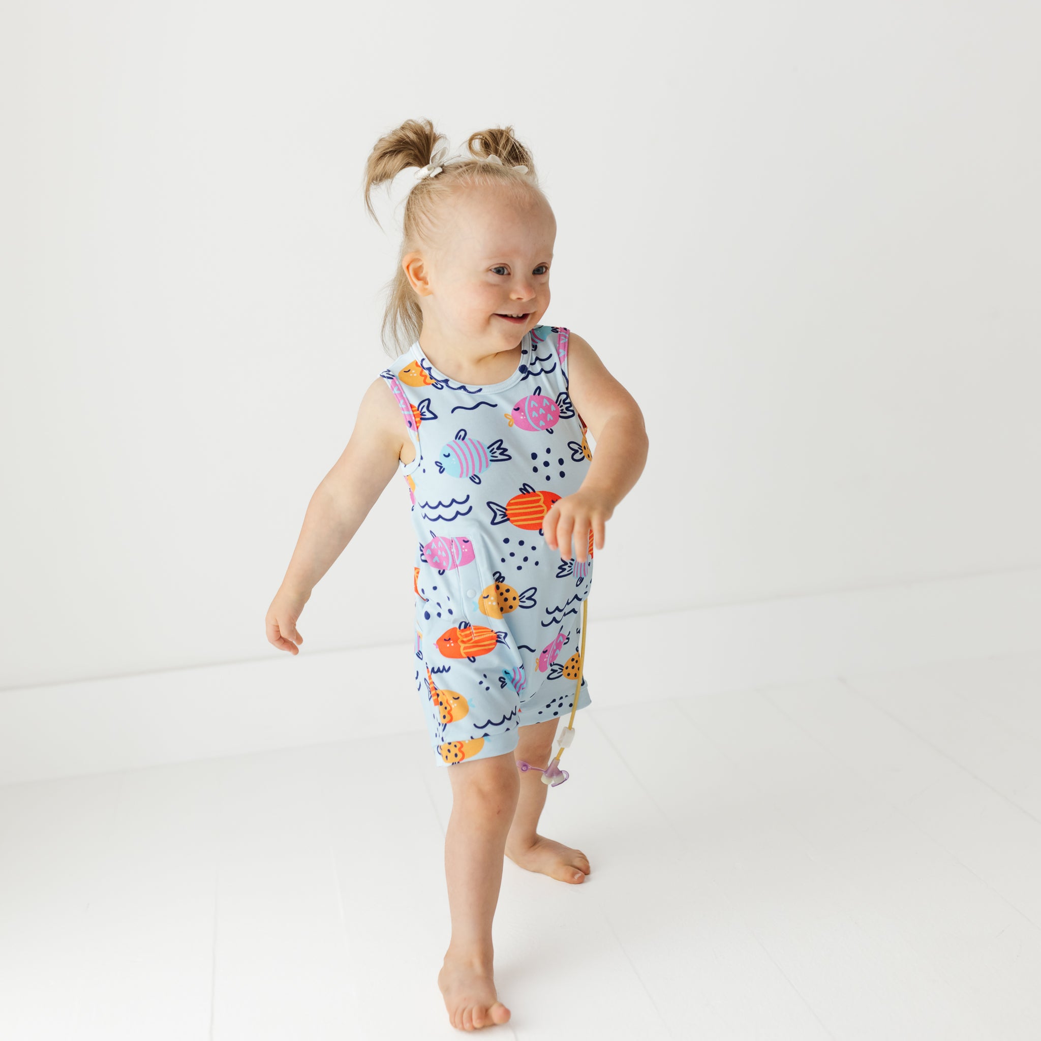 Child wearing a colorful sleeveless dress with sea-themed design on a white background