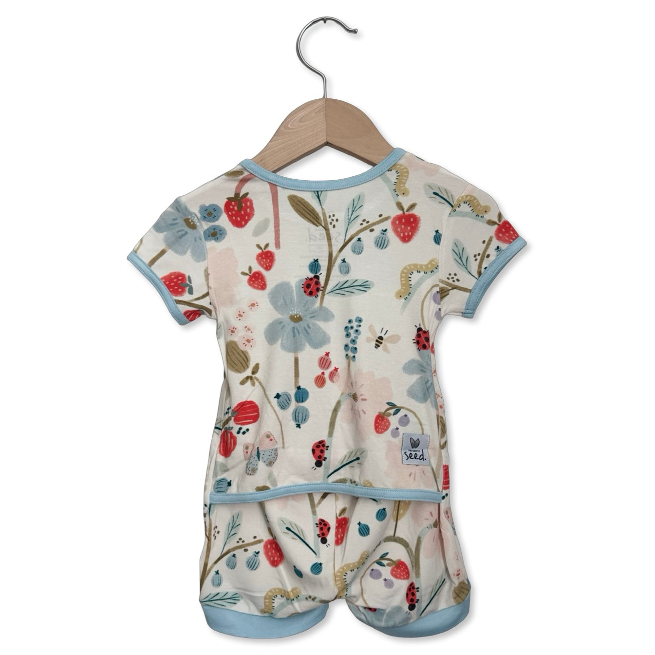 Baby romper with floral and fruit pattern on a hanger against a white background