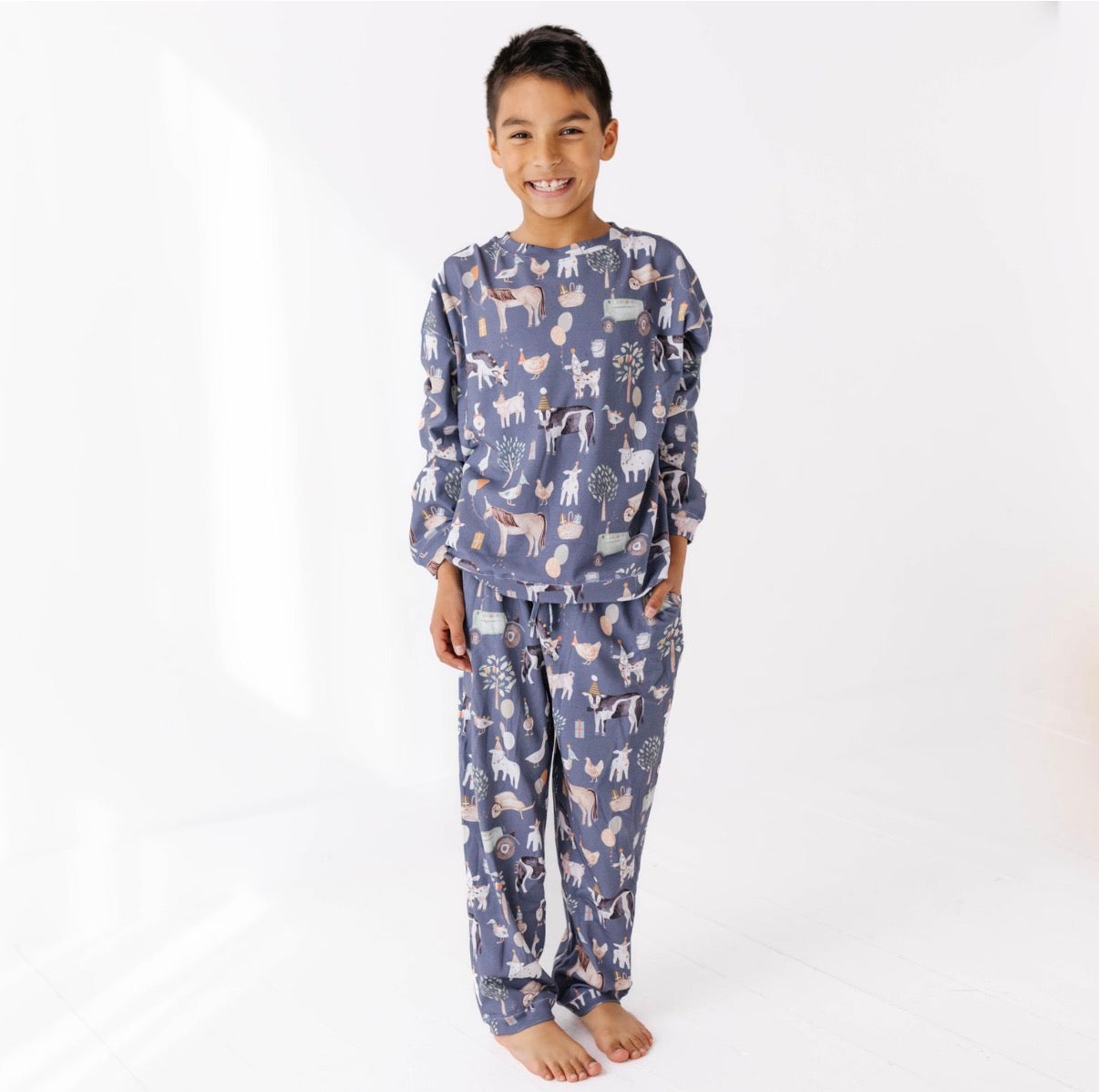 Child wearing a blue pajama set with animal pattern on a white background
