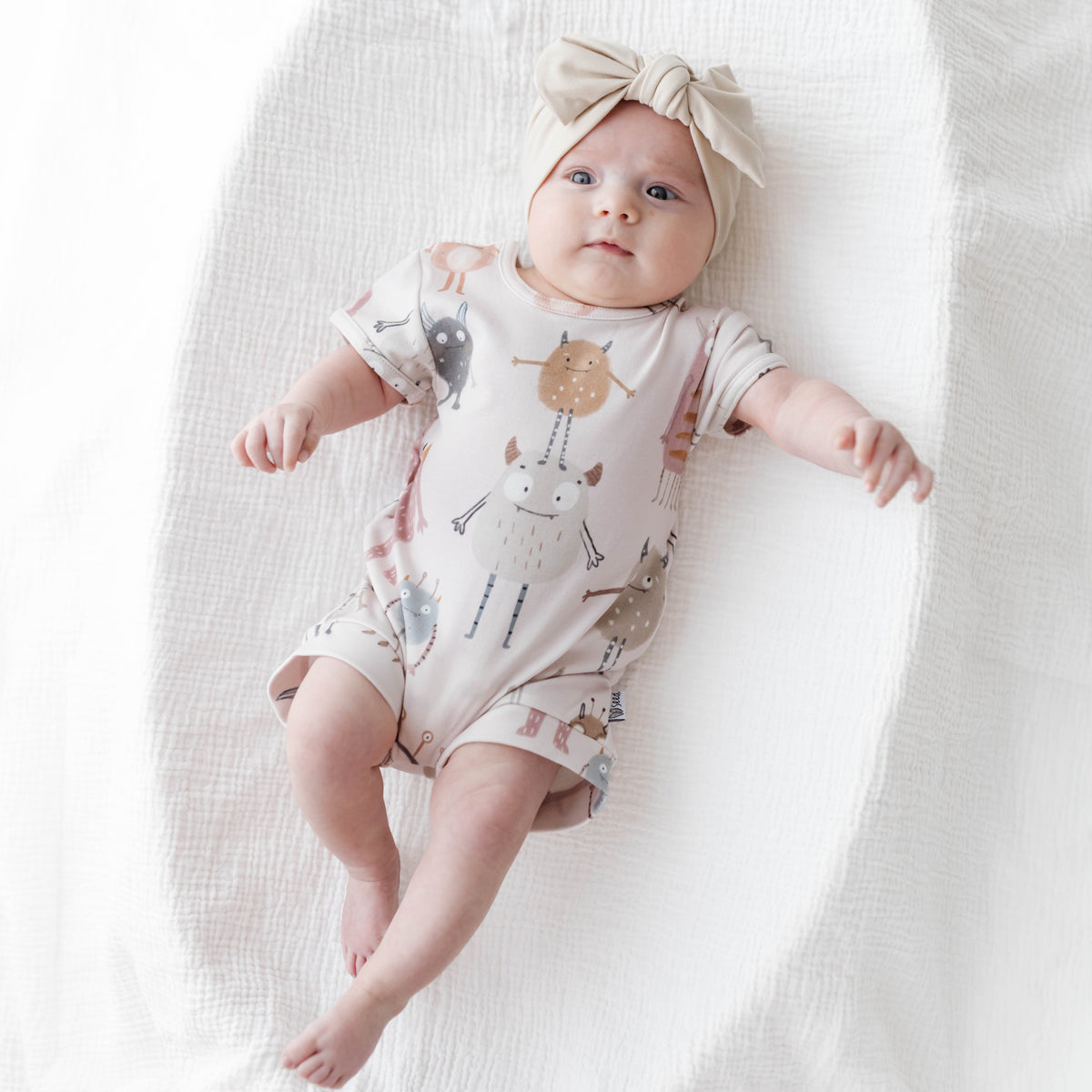 Baby wearing a patterned onesie and headband on a white background