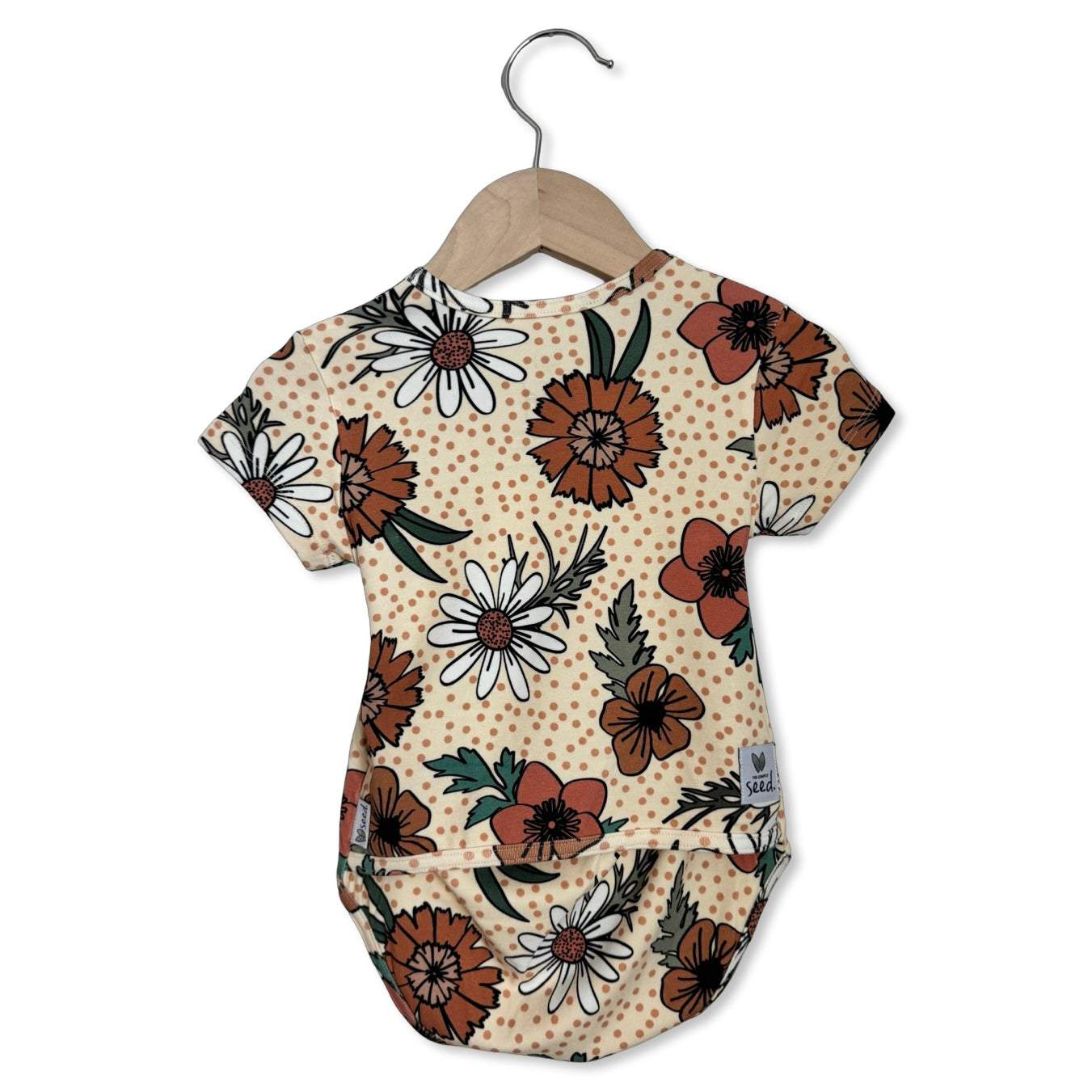 Floral-patterned baby onesie on a hanger against a white background