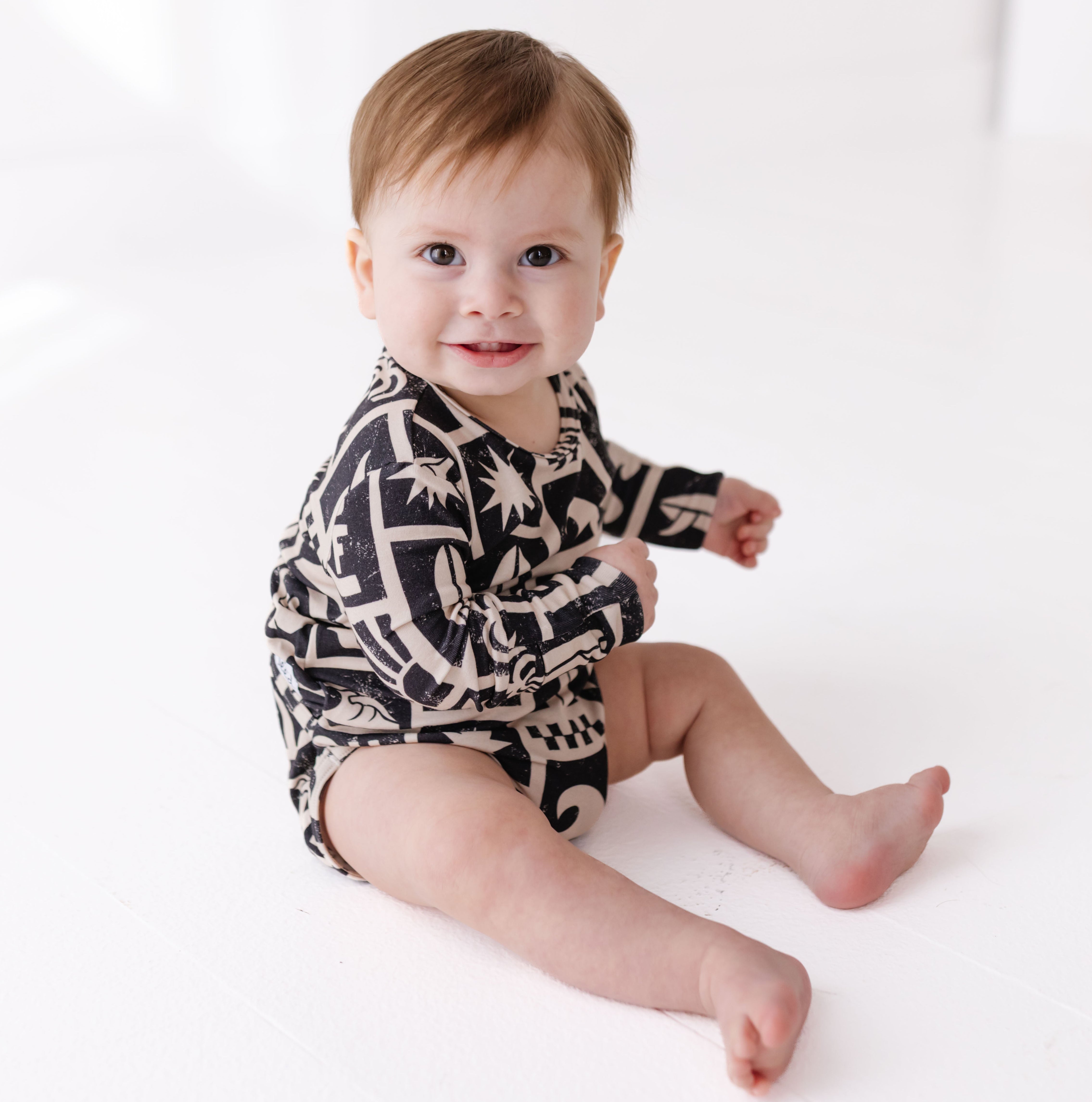 Baby wearing a black and white patterned onesie on a white background