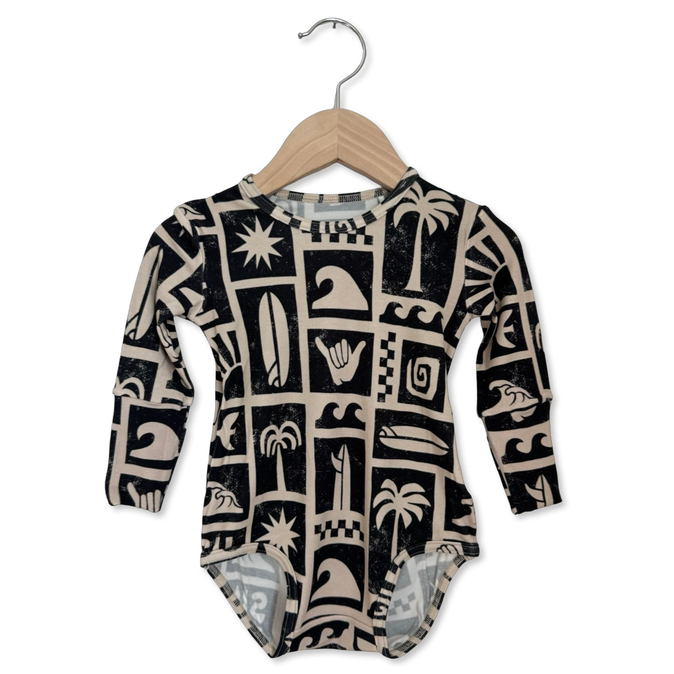 Baby onesie with black and white pattern on a hanger against a white background