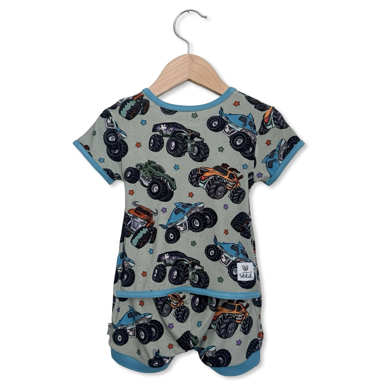 Baby romper with monster truck pattern on a hanger against a white background