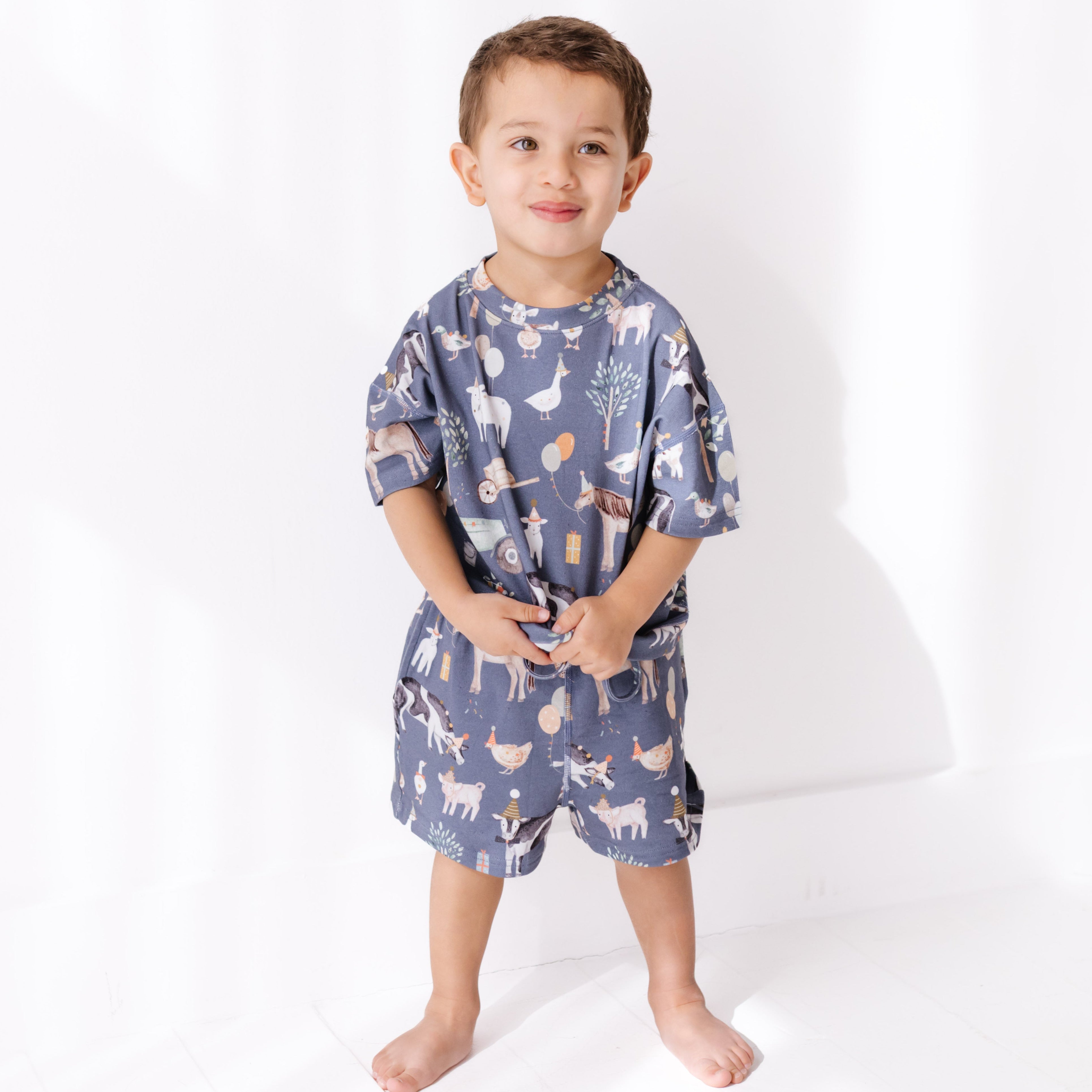 Child wearing a blue pajama set with animal prints on a white background