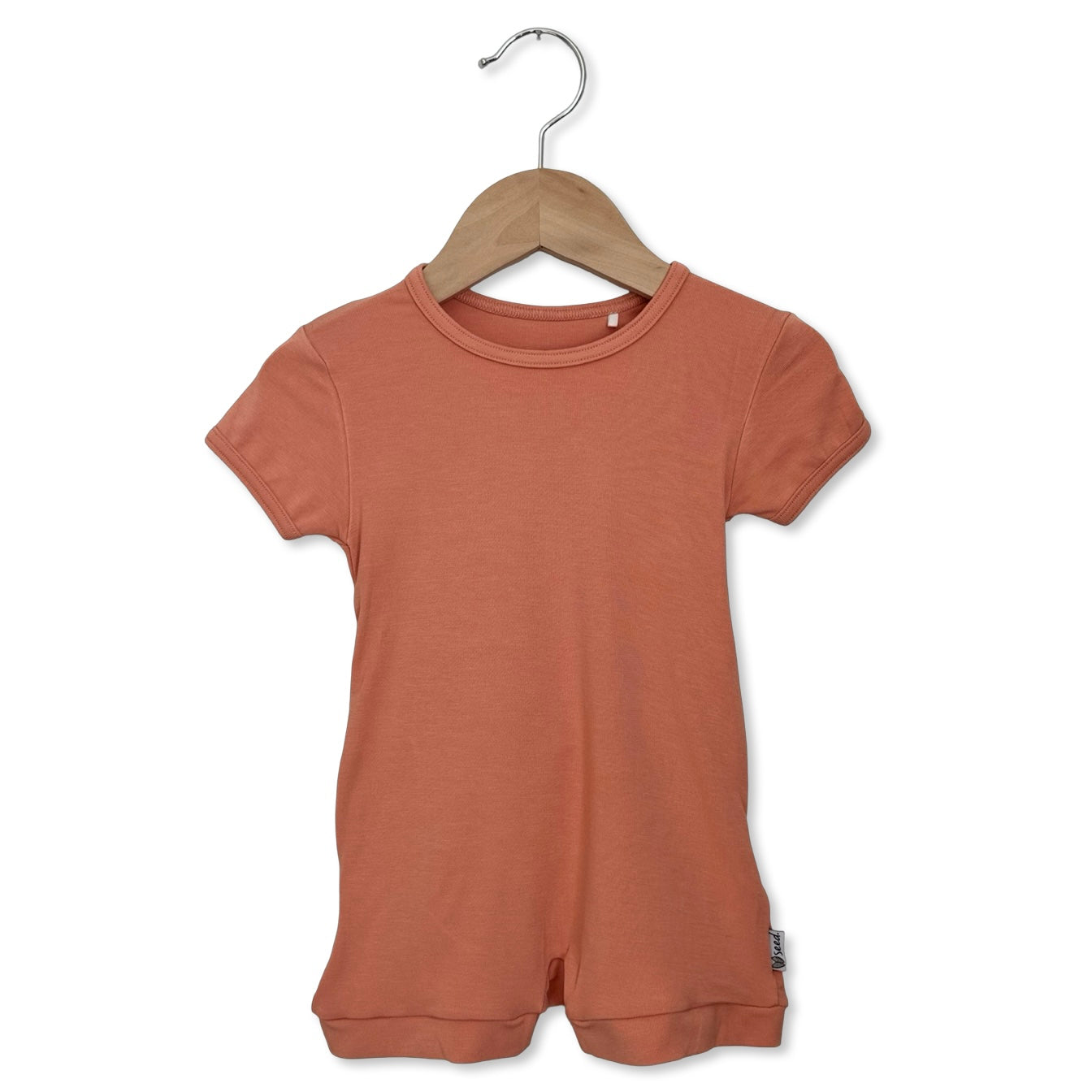 Peach romper on a hanger against a white background