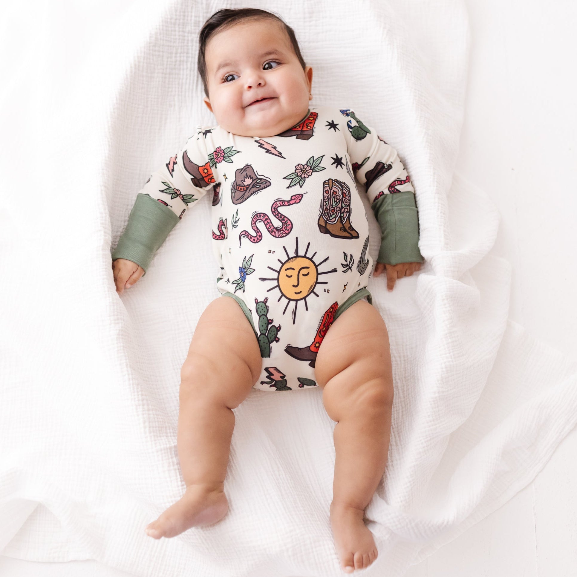 Baby wearing a patterned onesie on a white blanket