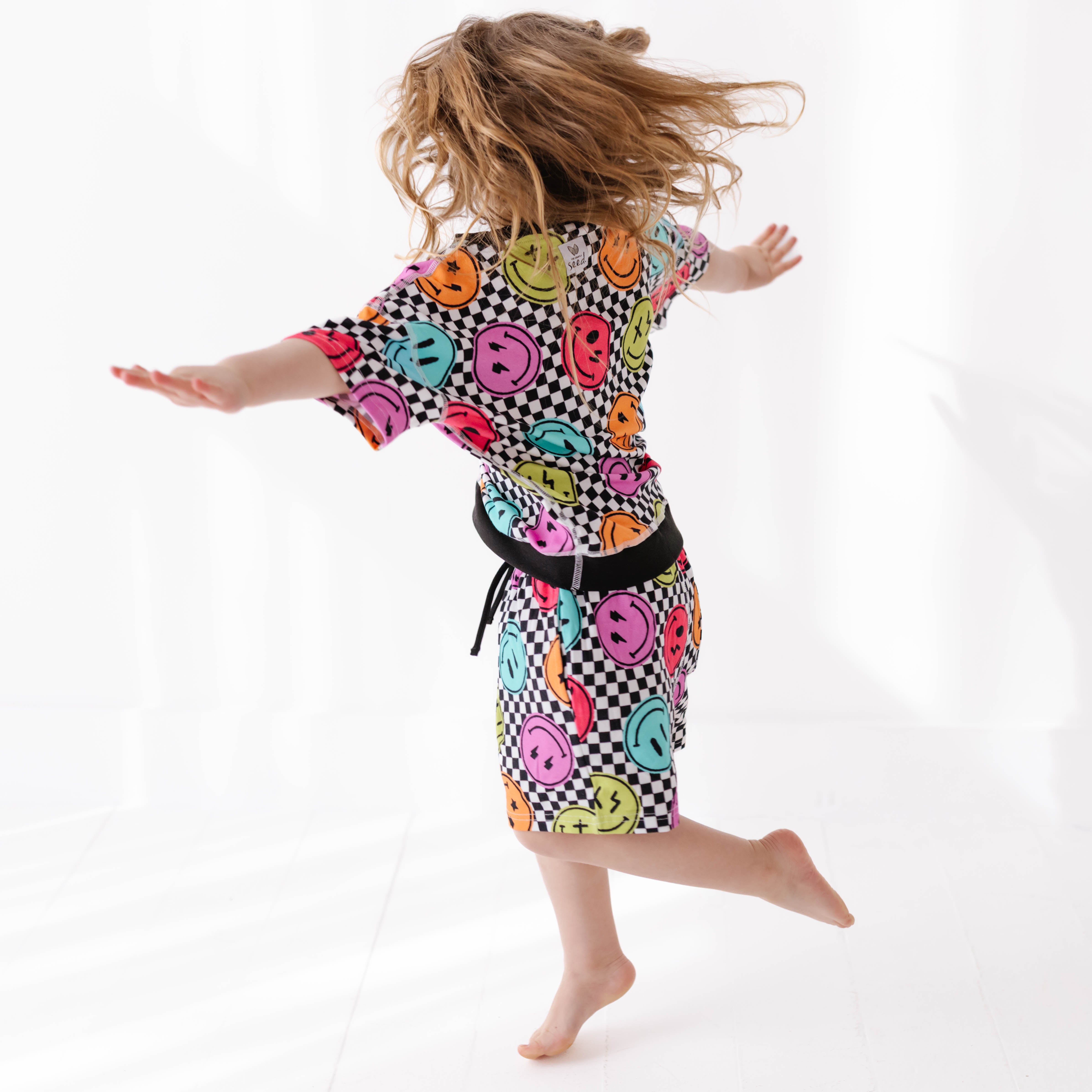 Person wearing a colorful dress with smiley face pattern on a white background
