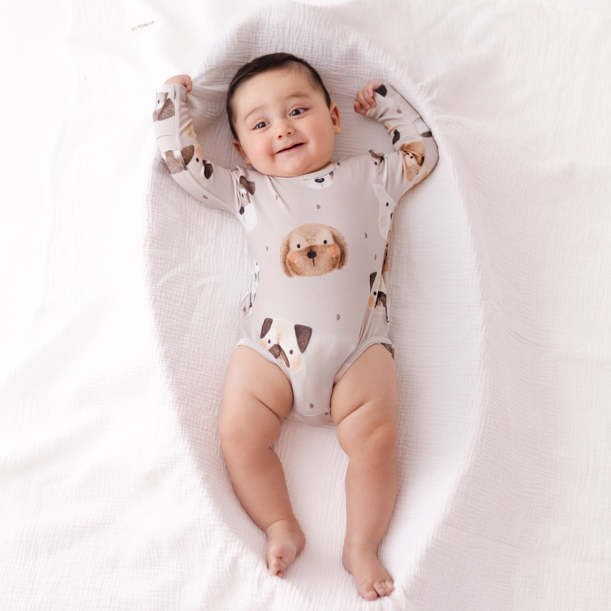 Baby wearing a onesie with animal prints, lying on a white surface
