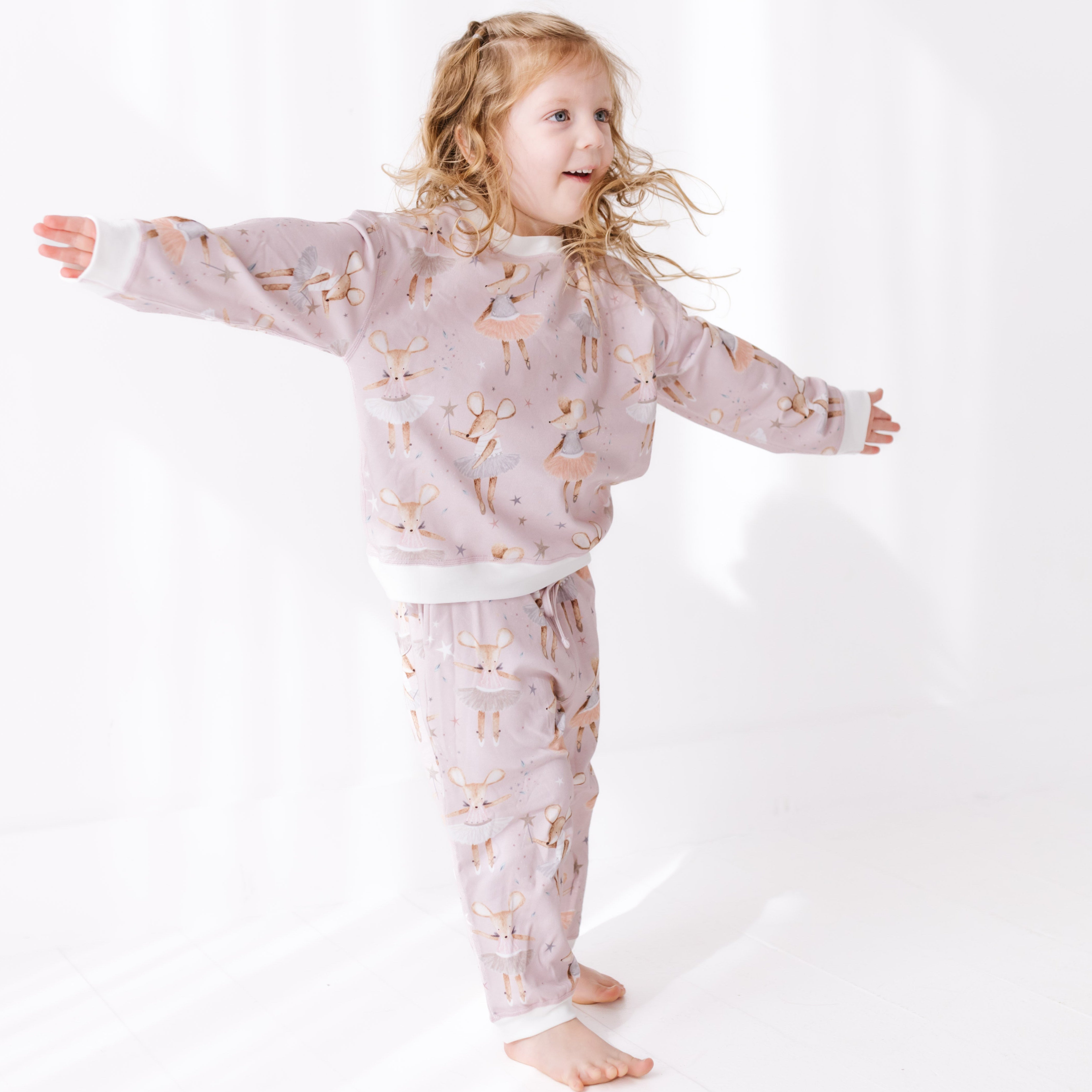 Child wearing a pink sweat set with dancing mice patterns on a white background