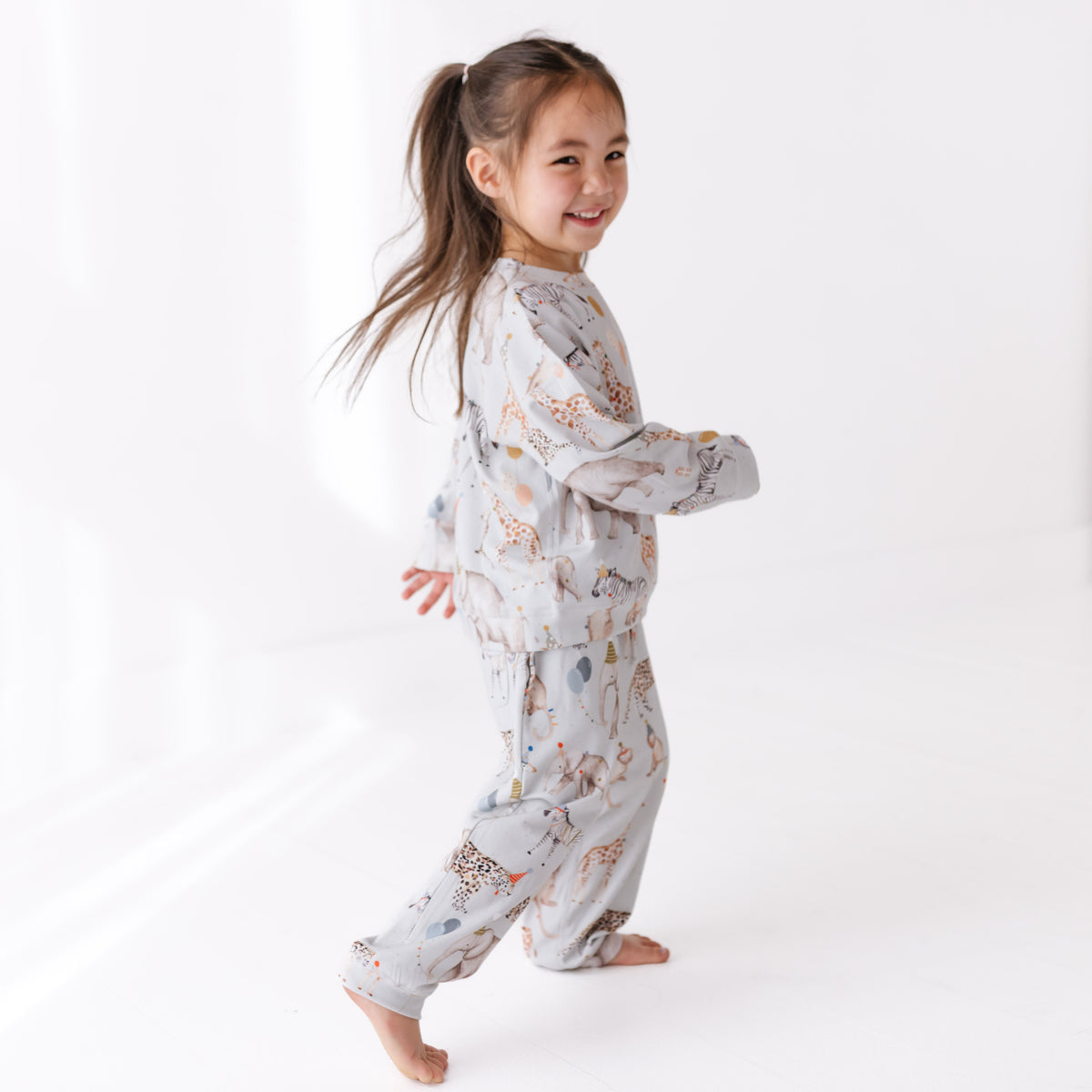 Child wearing a patterned sweat set on a white background