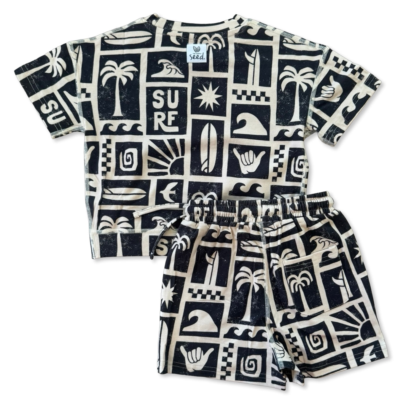 Children's t-shirt and shorts set with black and white surf-themed pattern on a white background