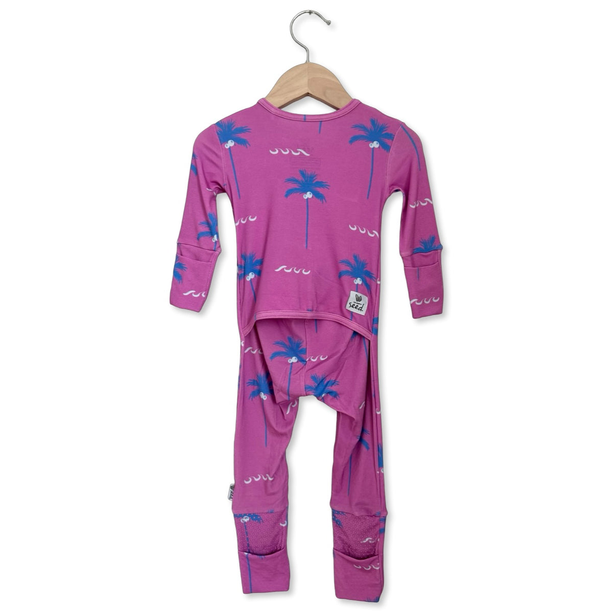 Purple children's pajama set with palm tree design on a hanger against a white background