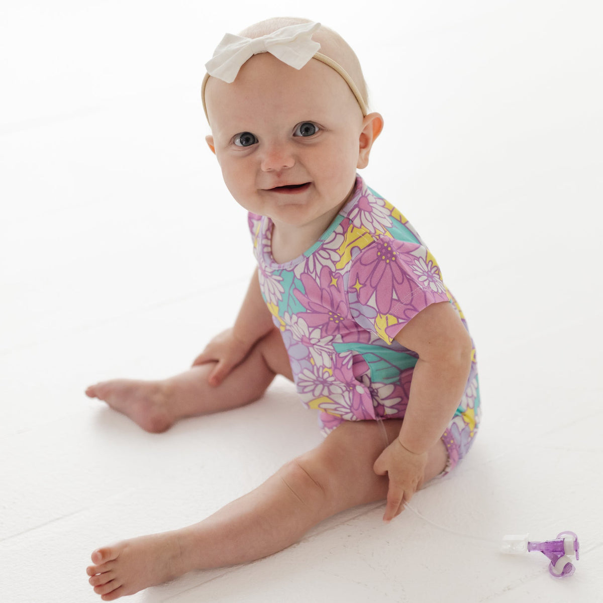 Baby wearing a colorful floral onesie on a white background