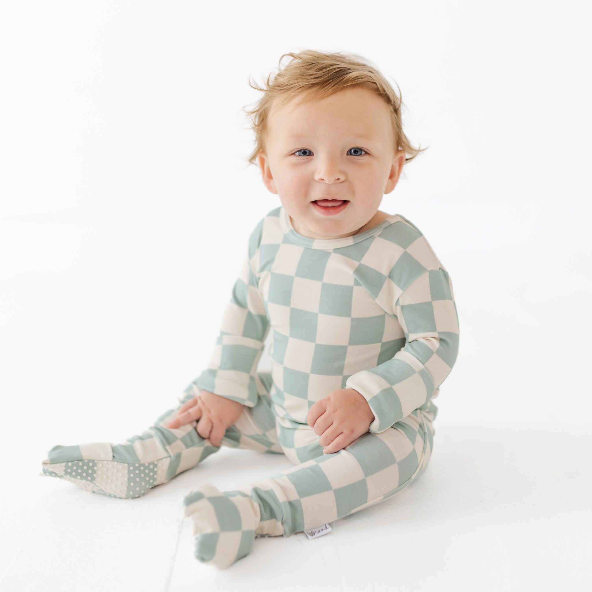 Baby wearing a checkered outfit on a white background