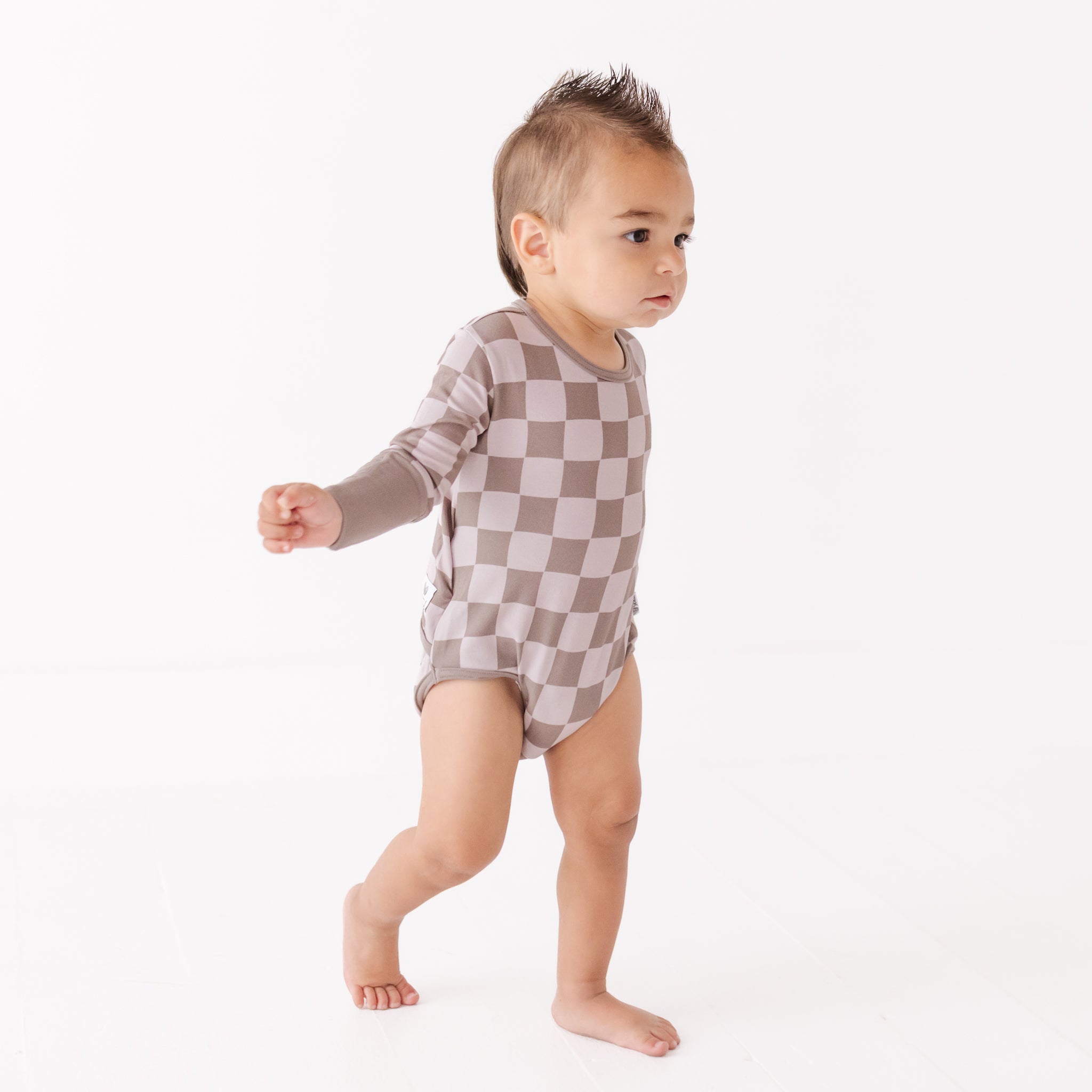 Baby wearing a checkered onesie on a white background