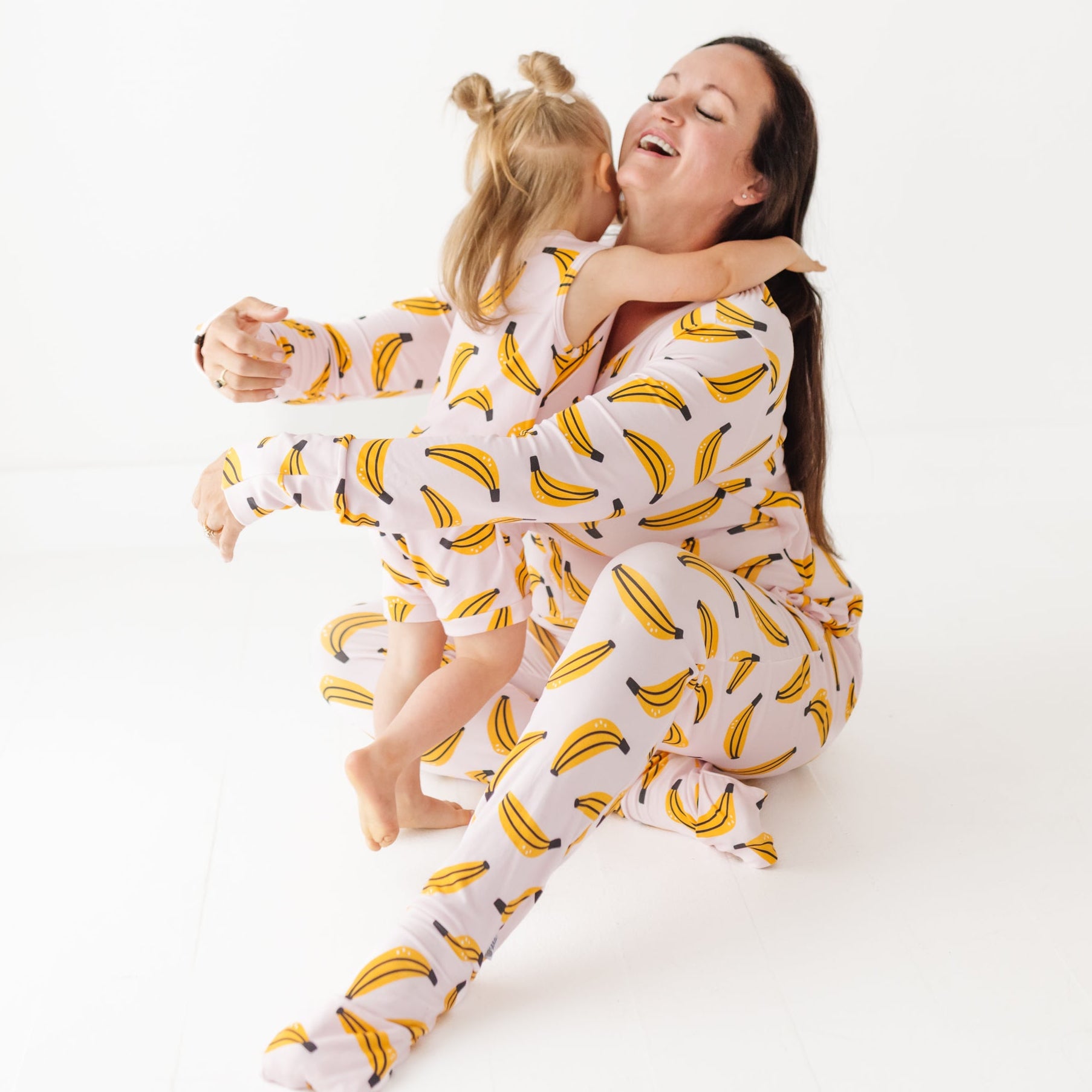 Woman and child wearing banana-patterned pajamas on a white background