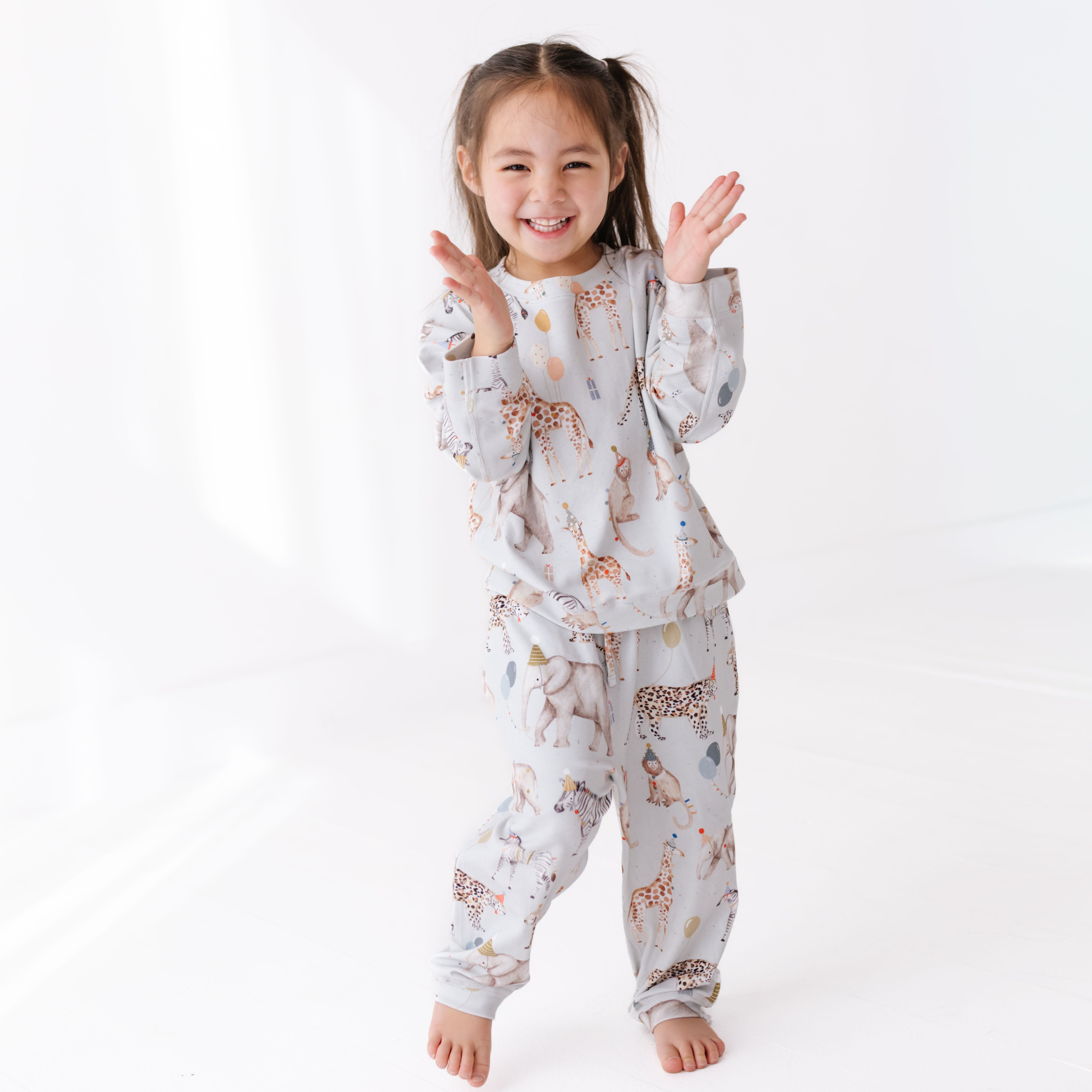 Child wearing a patterned sweat set on a white background