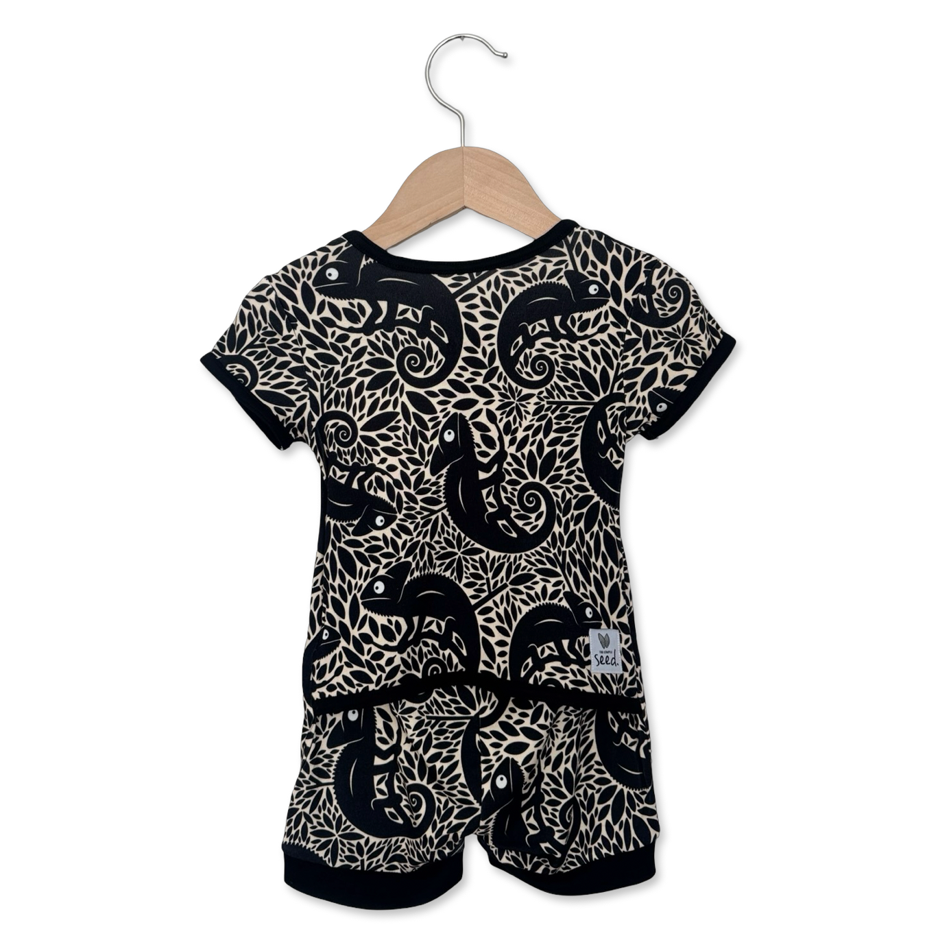 Baby romper with black and white pattern on a hanger against a white background