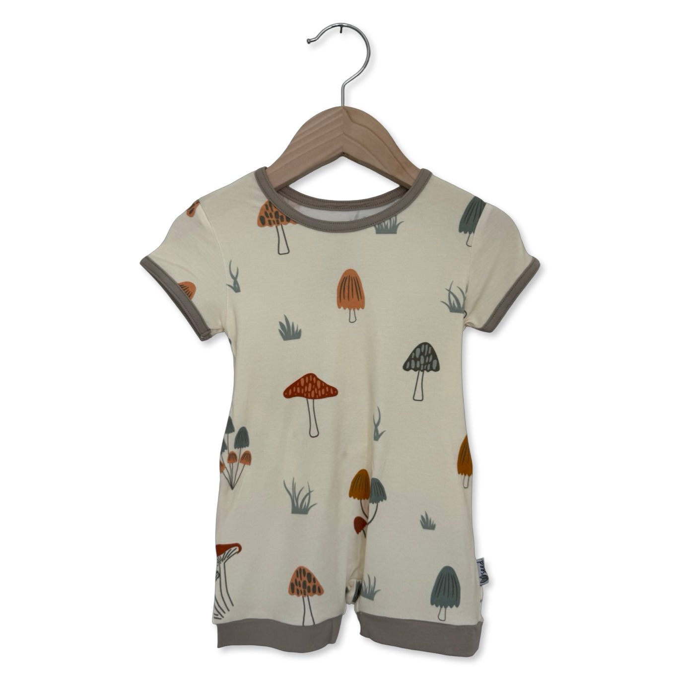 Children's romper with mushroom pattern on a hanger against a white background