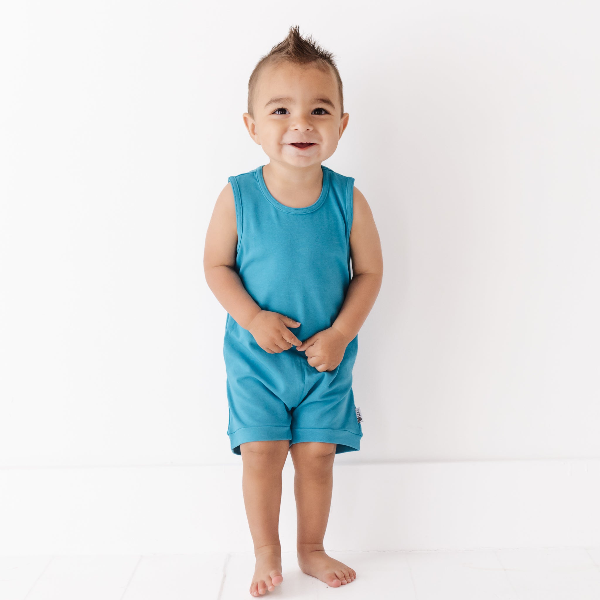 Child wearing a blue sleeveless top and shorts on a white background