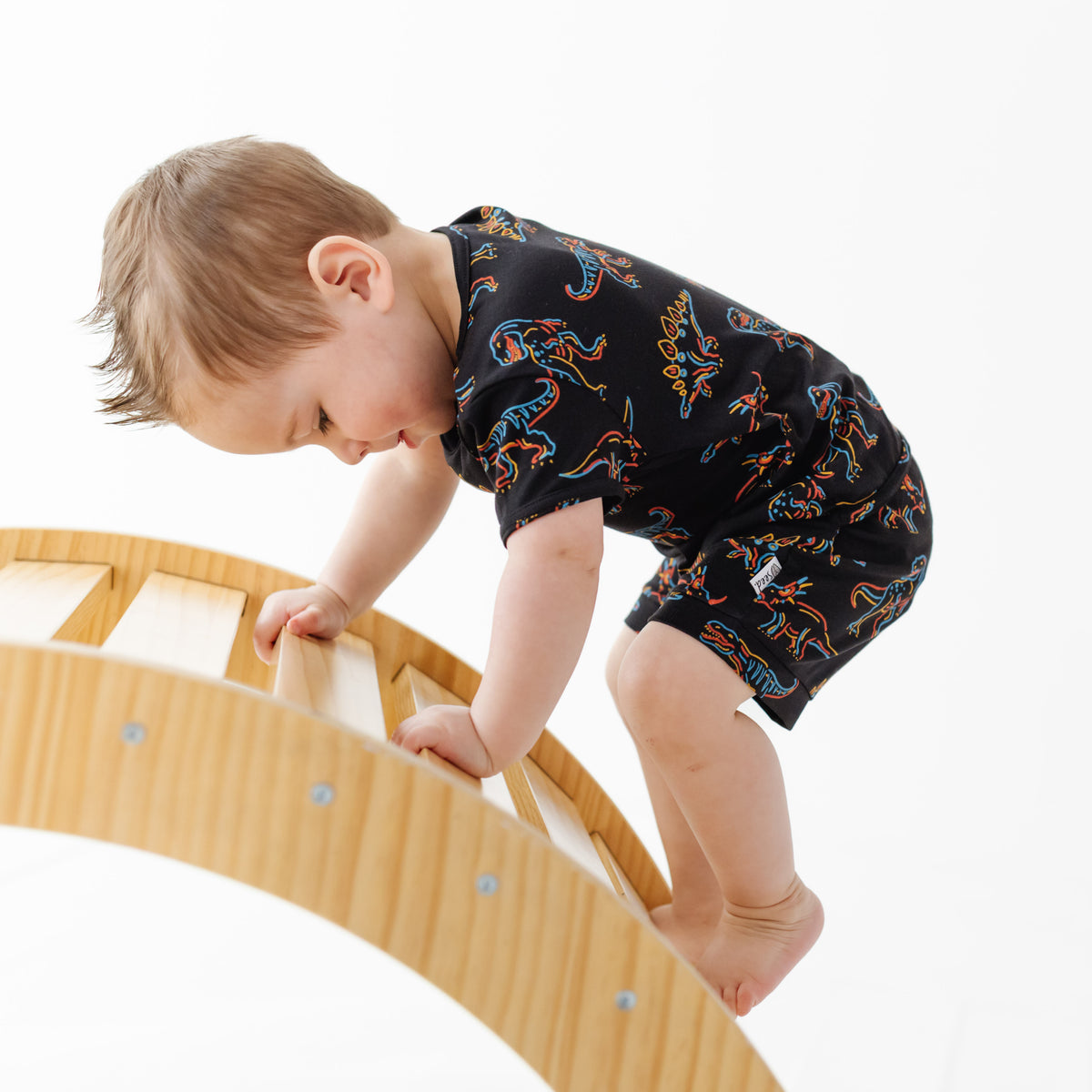 Child climbing on a wooden climbing toy with a white background