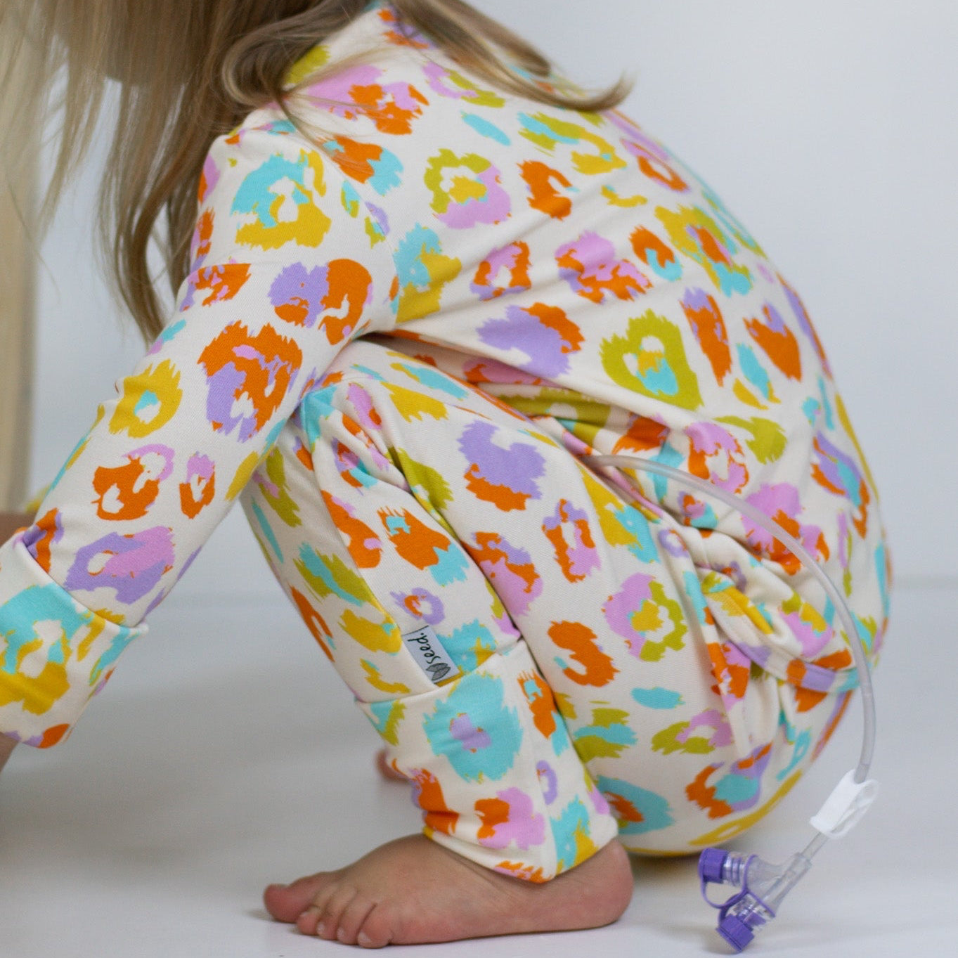 Child wearing colorful animal print pajama pants on a white background
