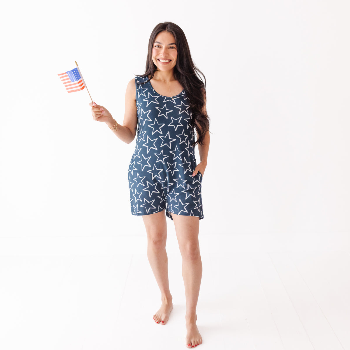 Woman wearing a blue star-patterned dress holding an American flag on a white background